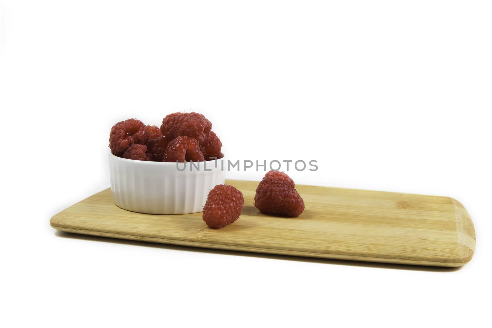 Ripe tasty bright Fresh raspberry in a wicker basket on a cutting board on a white background. High quality photo