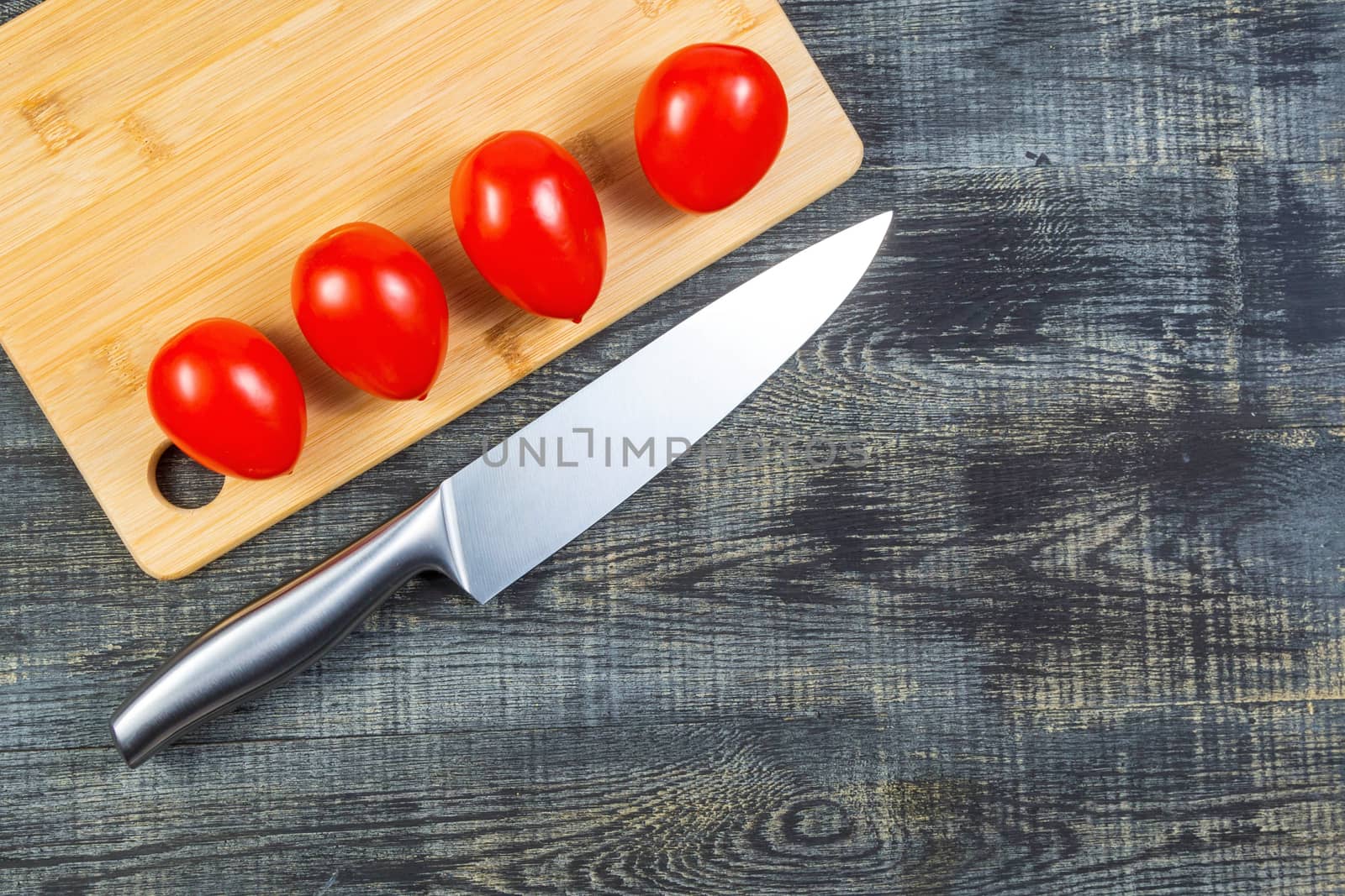 High Angle Still Life View of tomatoes and knife on Wooden Cutting Board on Rustic Wood Table