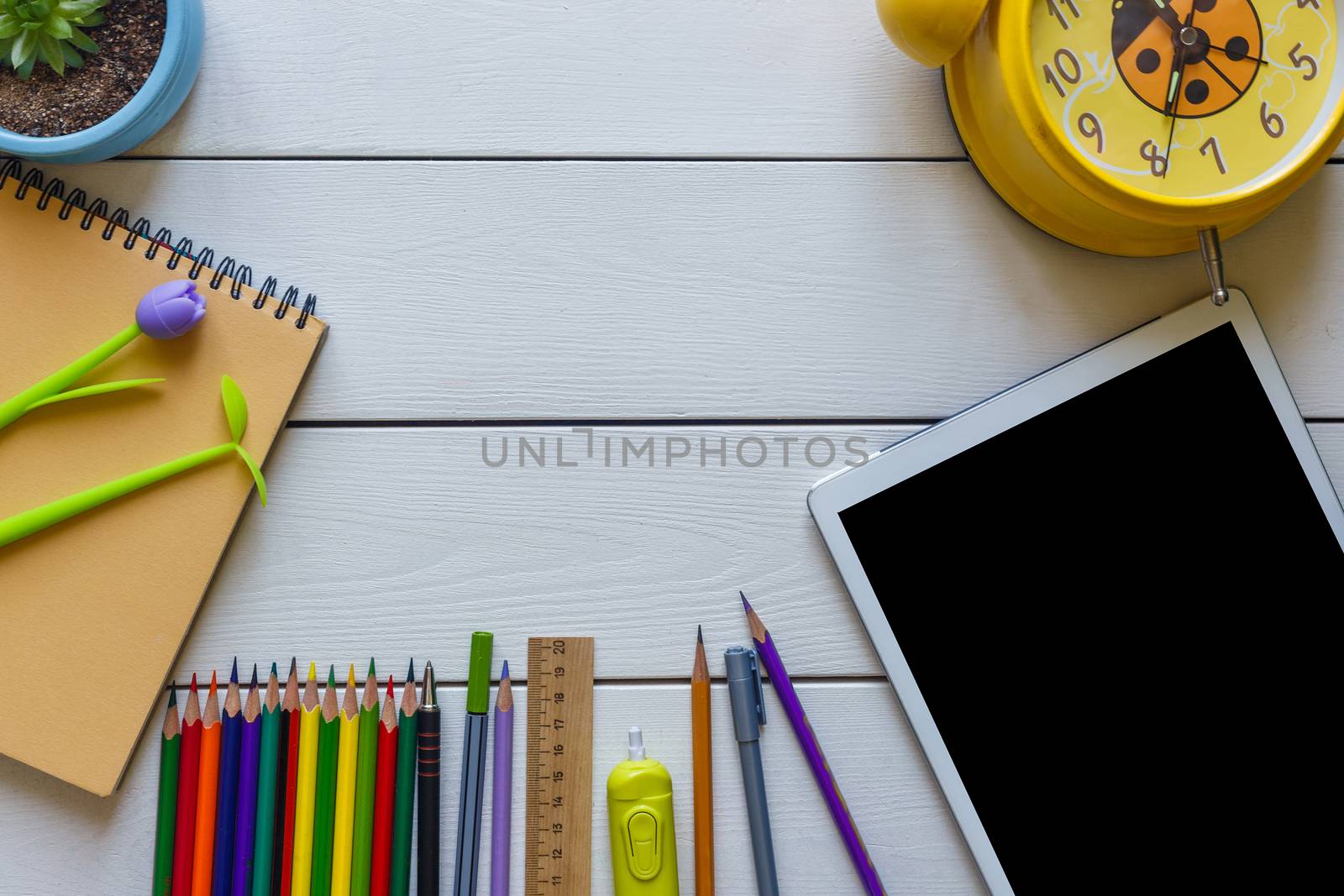 Back to school concept school office supplies on a white wooden backgrounf copy space of papers, pencils, alarm clock and tablet.