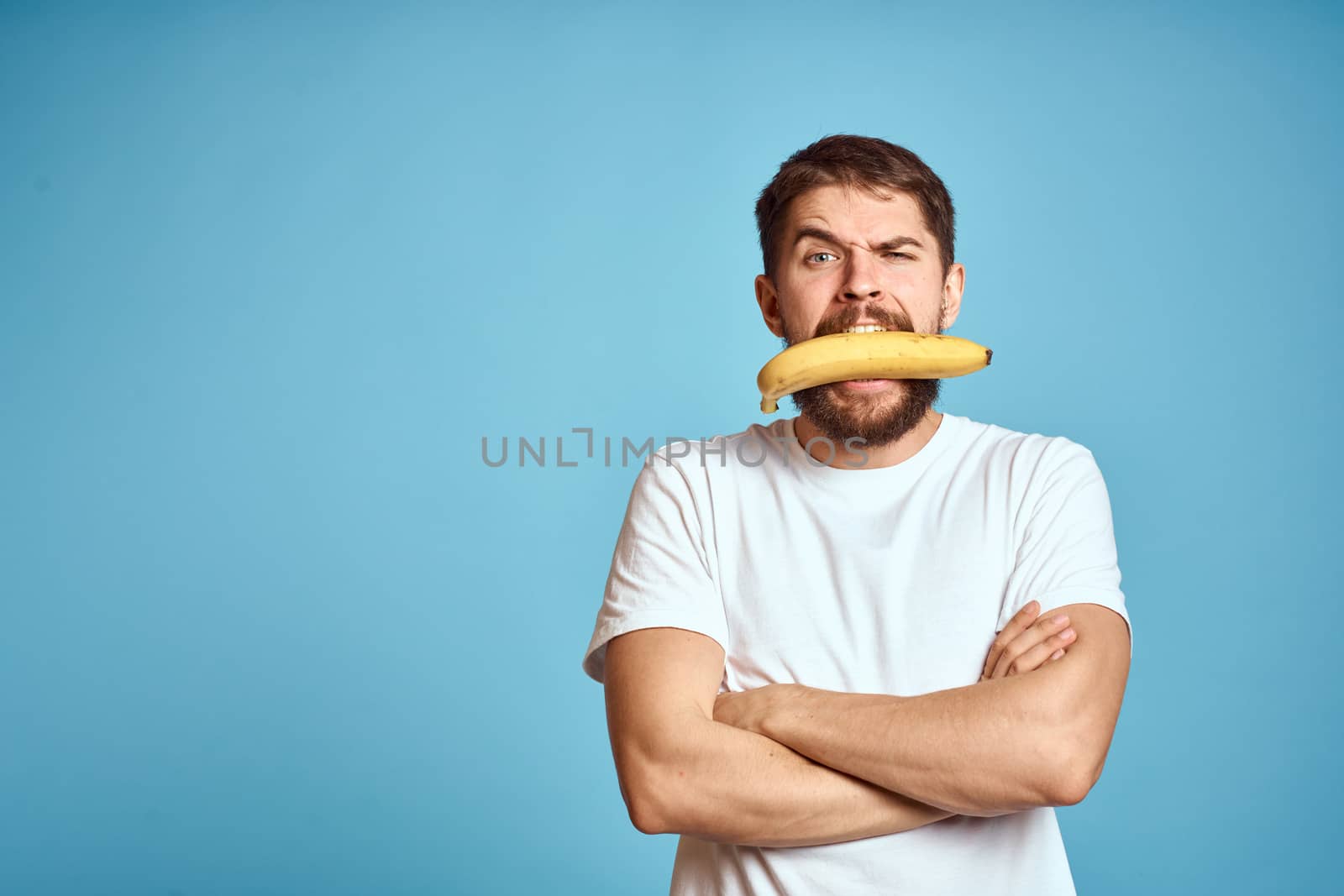 a man with a banana is caught in a white t-shirt on a blue background concept of communication by phone. High quality photo