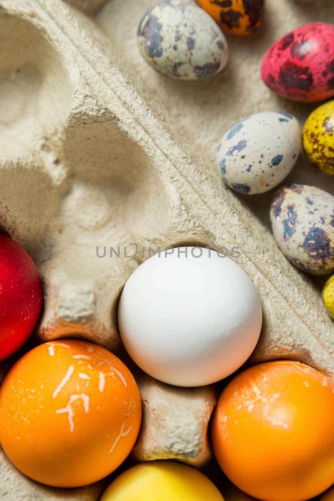 Dyed easter eggs in cardboard box on wooden background. by galinasharapova