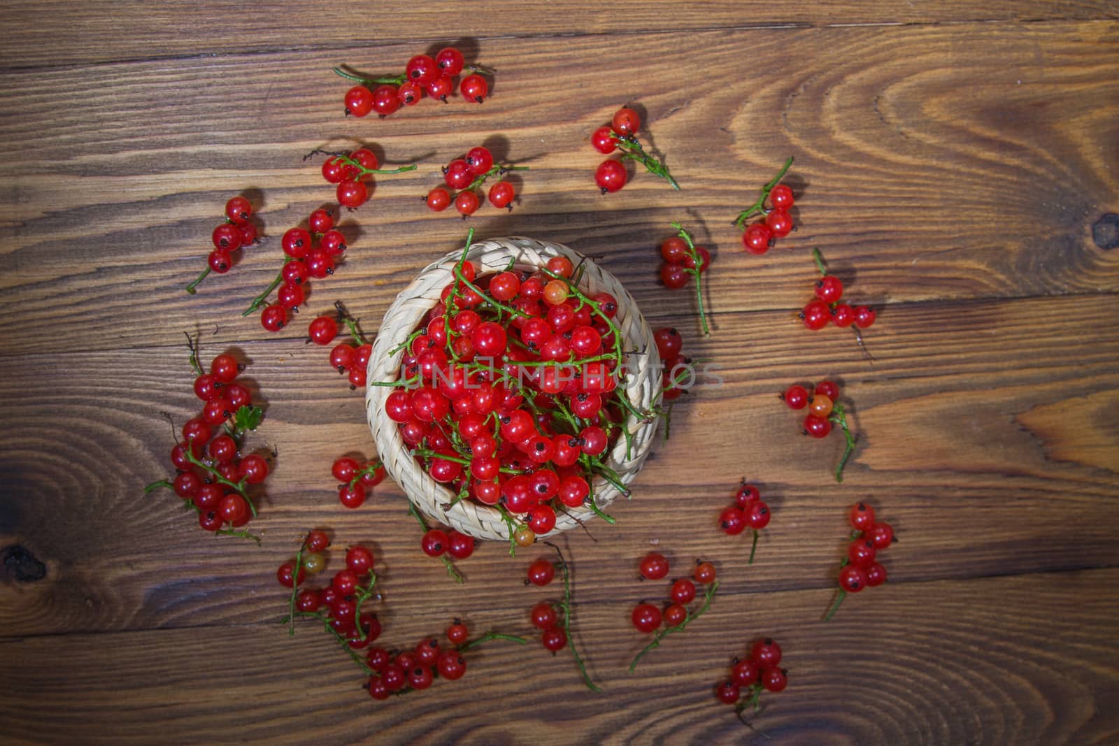 red currant berries in a ceramic bowl on a rustic wooden background. by galinasharapova