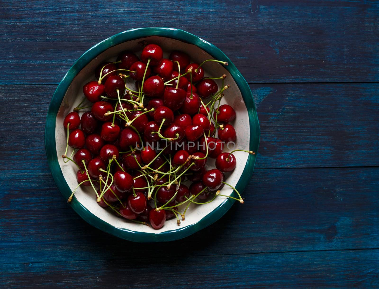 Fresh cherry on plate on wooden blue background. fresh ripe cherries. sweet cherries.