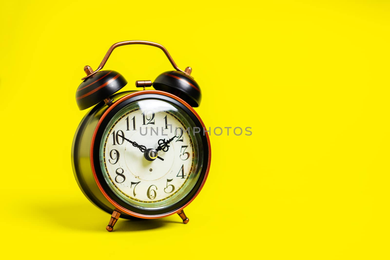 Vintage clock or alarm clock with copy space on yellow background