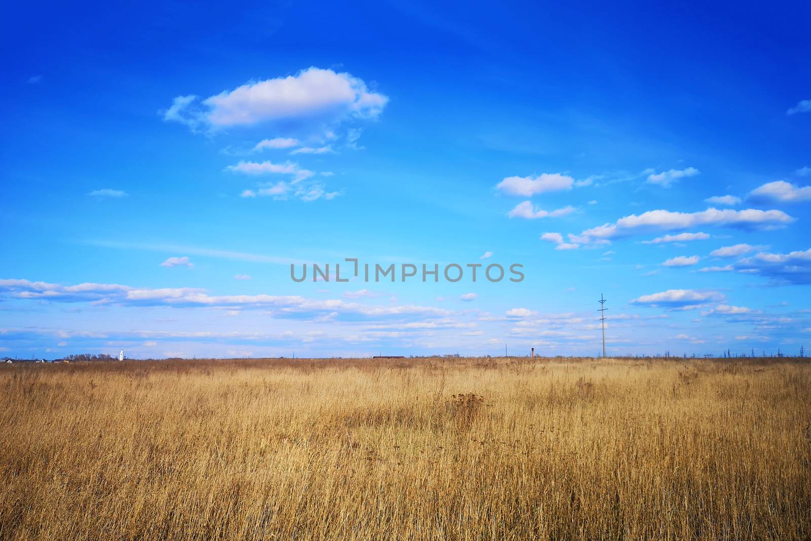 Large white clouds in the blue sky above a village in Russia.