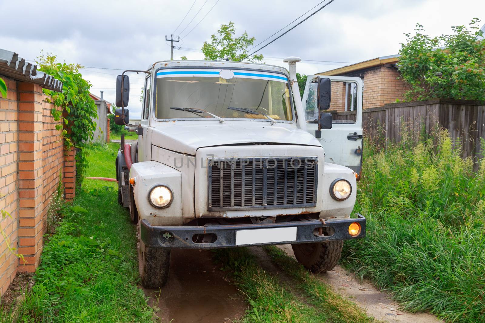 A Sewage truck working in village environment.