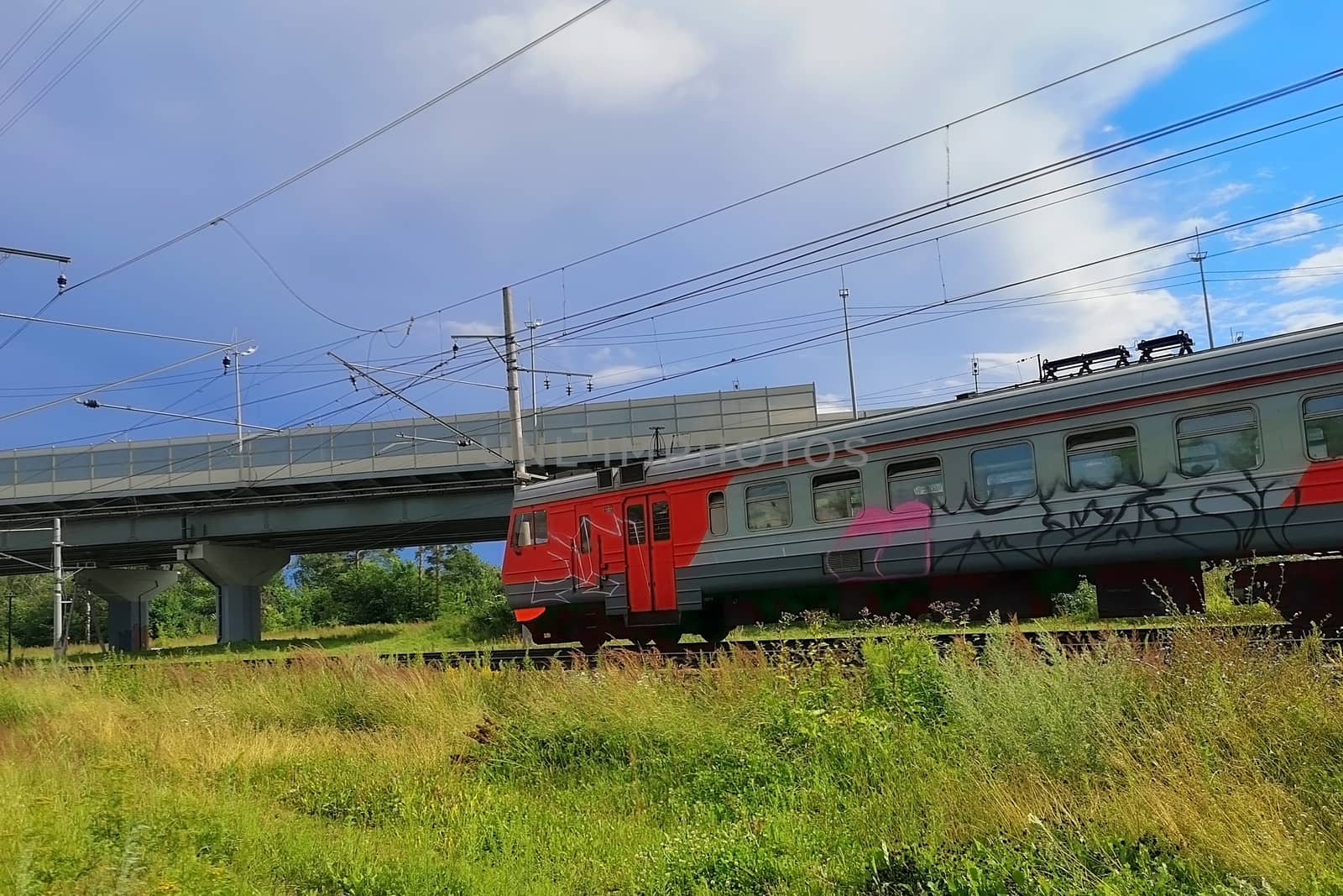 A train with graffiti passes under the bridge over the railway by galinasharapova