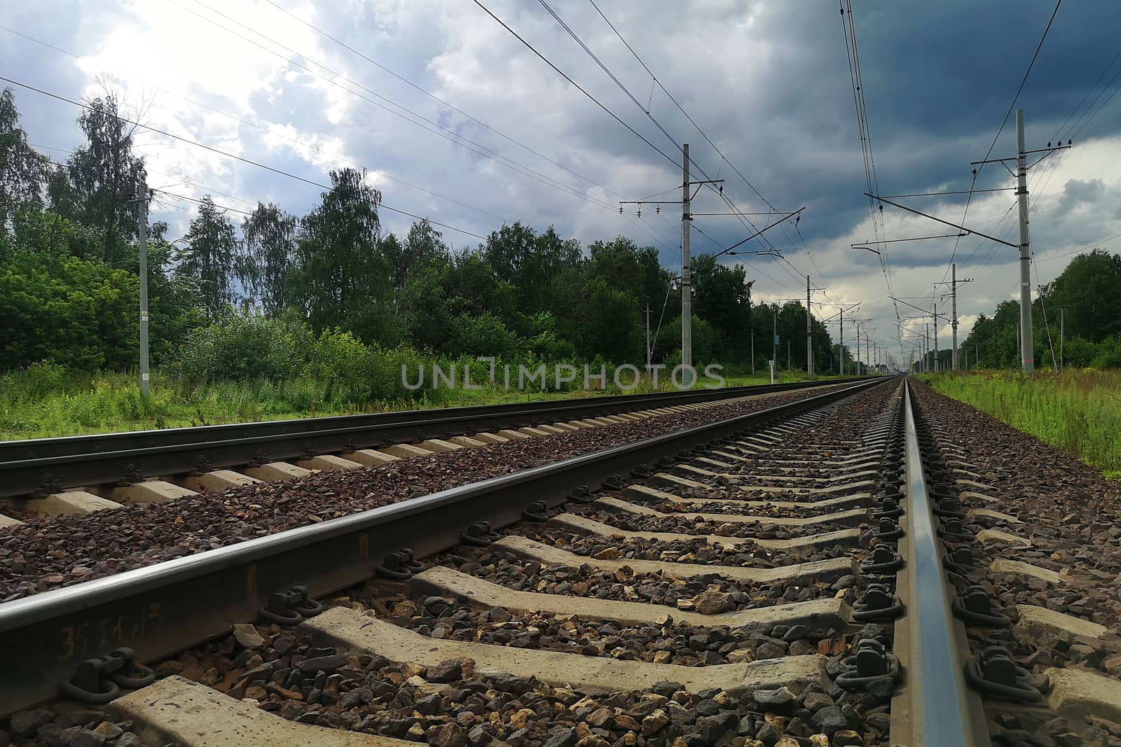 Railroad Tracks Against dark Cloudy Sky in a rural landscape. Evening, summer time