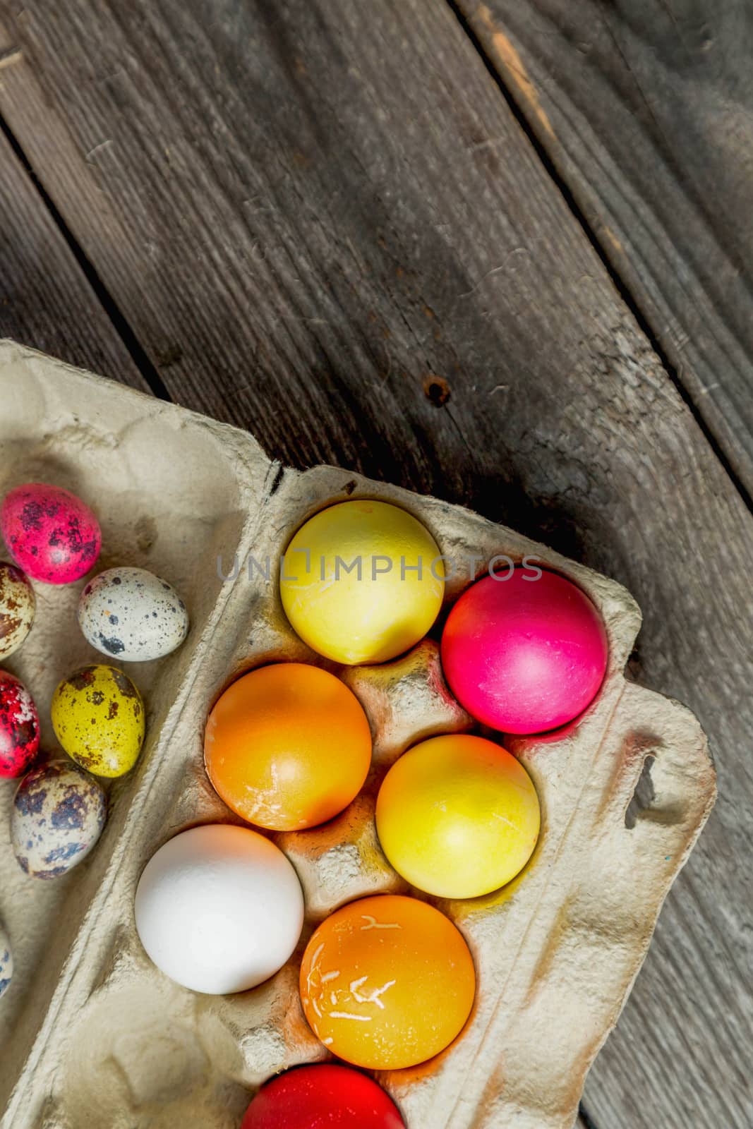 Dyed easter eggs in cardboard box on wooden background. Easter background with space for a text.Vertical high quality photo