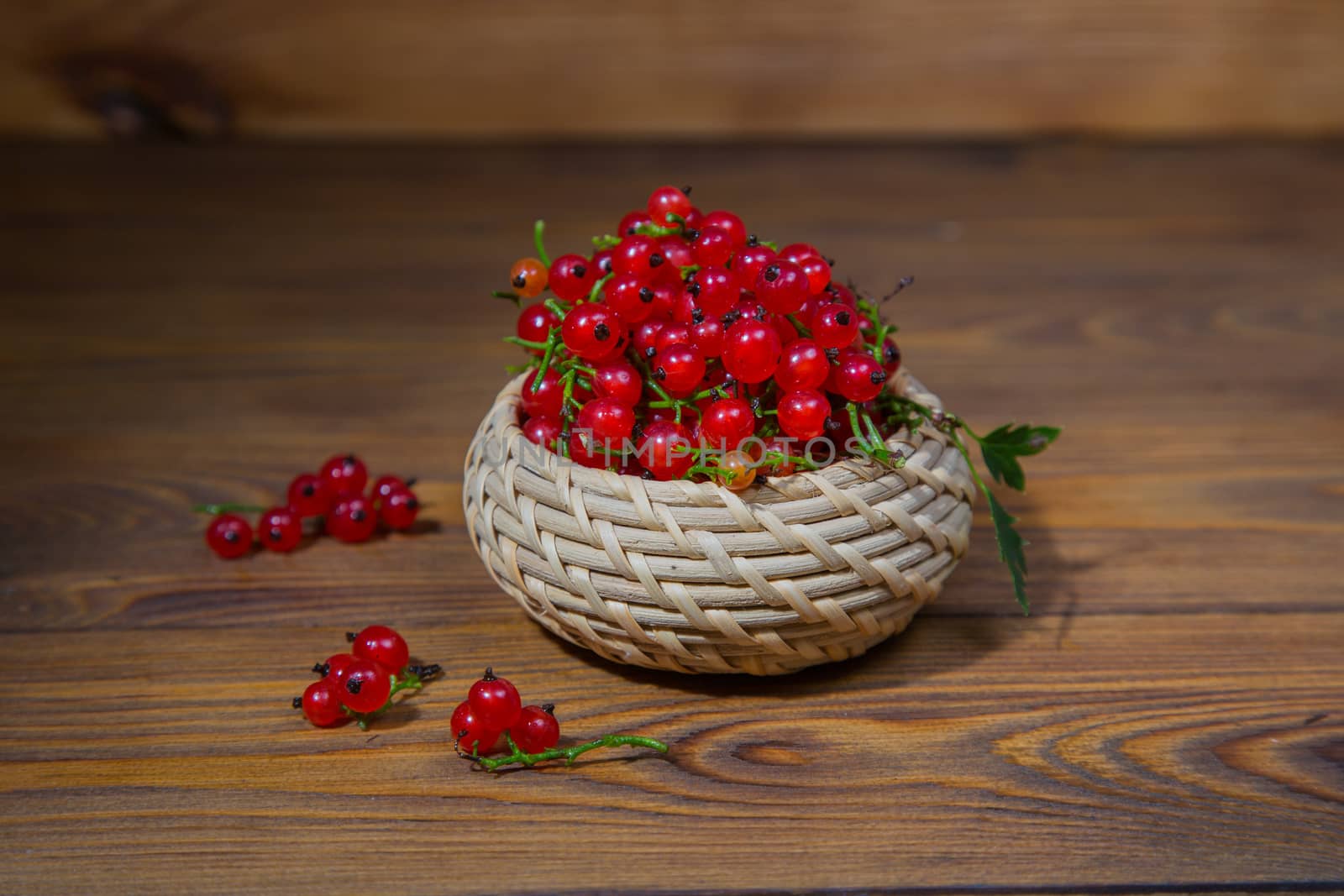 red currant berries in a ceramic bowl on a rustic wooden background. by galinasharapova