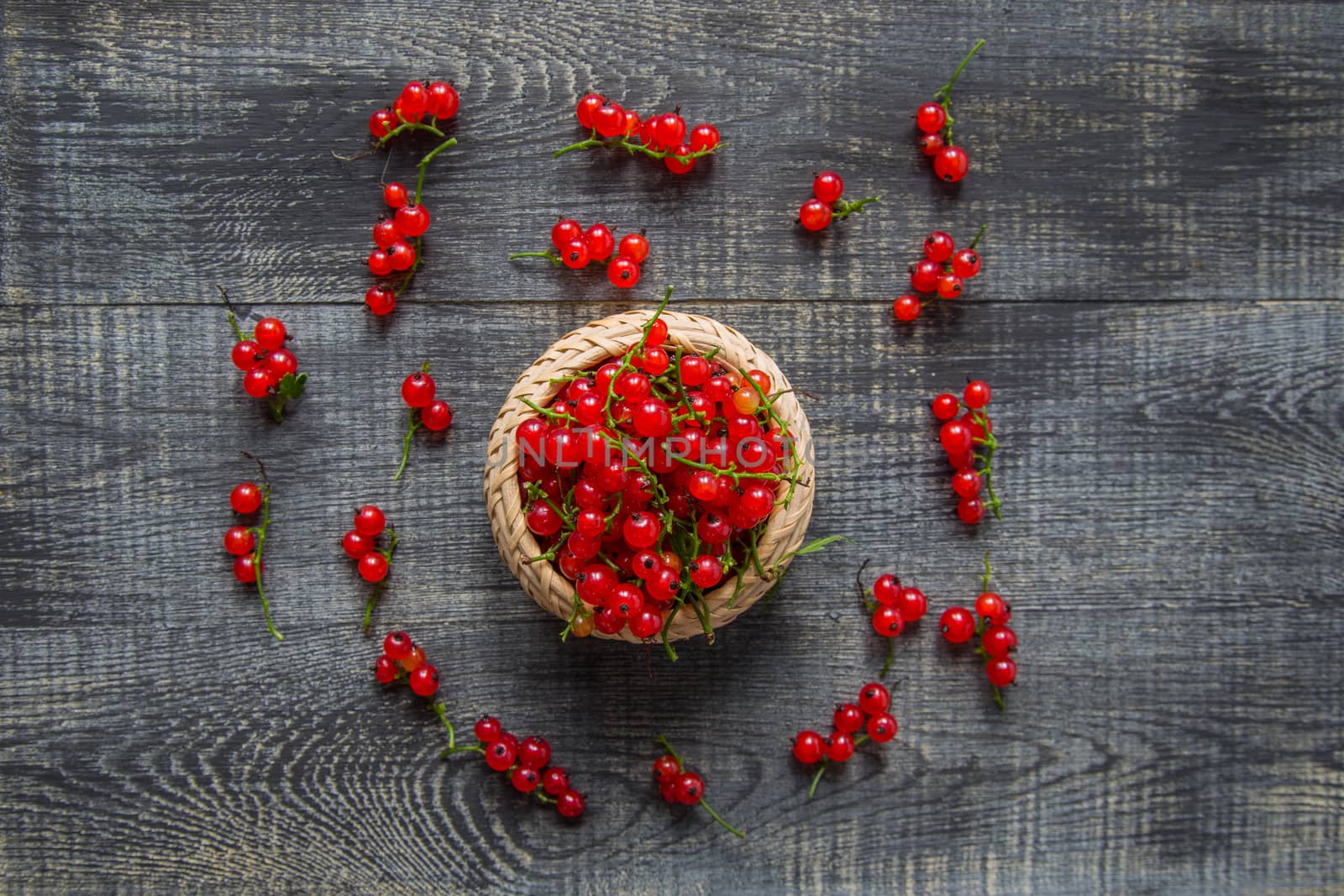 red currant berries in a ceramic bowl on a rustic wooden background. close up and selective focus