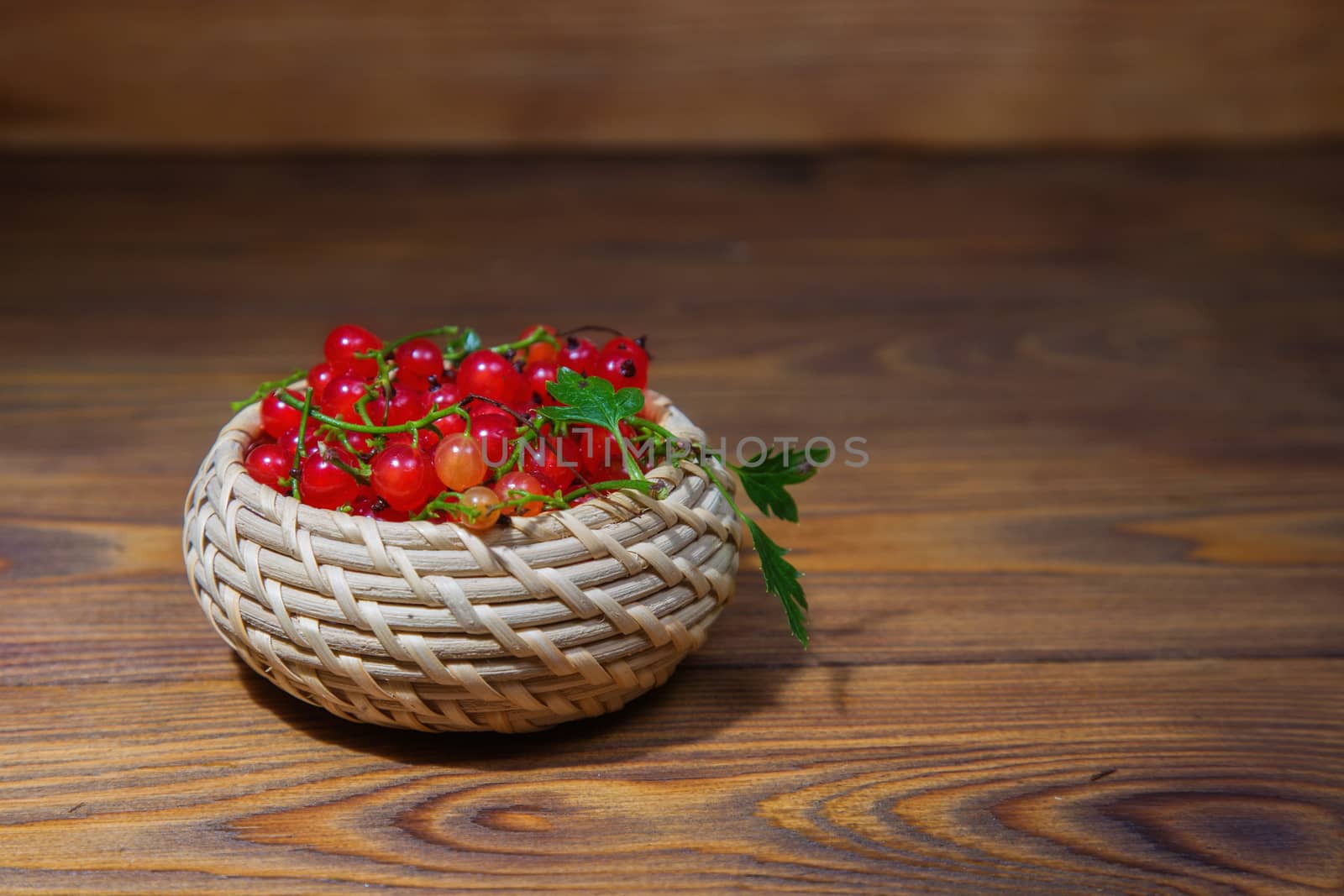 red currant berries in a ceramic bowl on a rustic wooden background. by galinasharapova