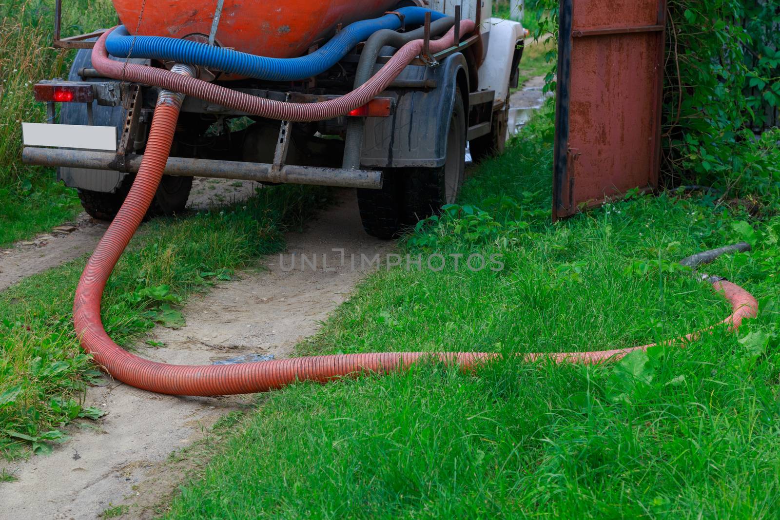 A Sewage truck working in village environment.