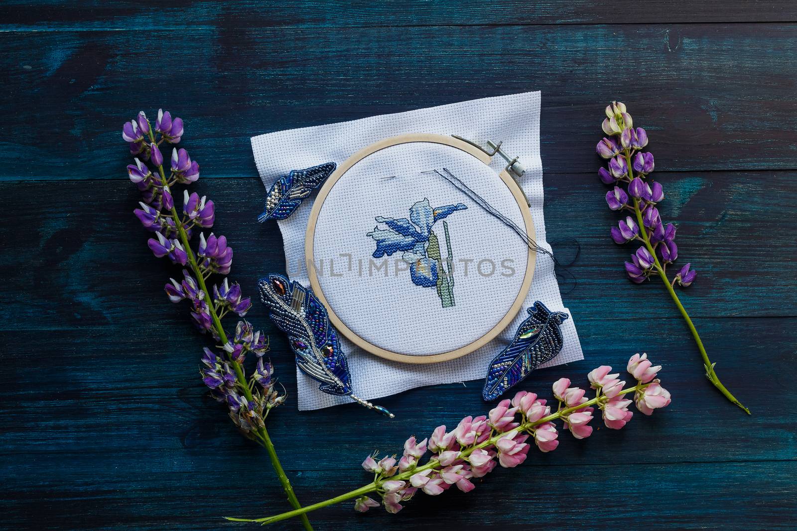 Handmade cross-stitch with floral pattern on canvas on wooden background by galinasharapova