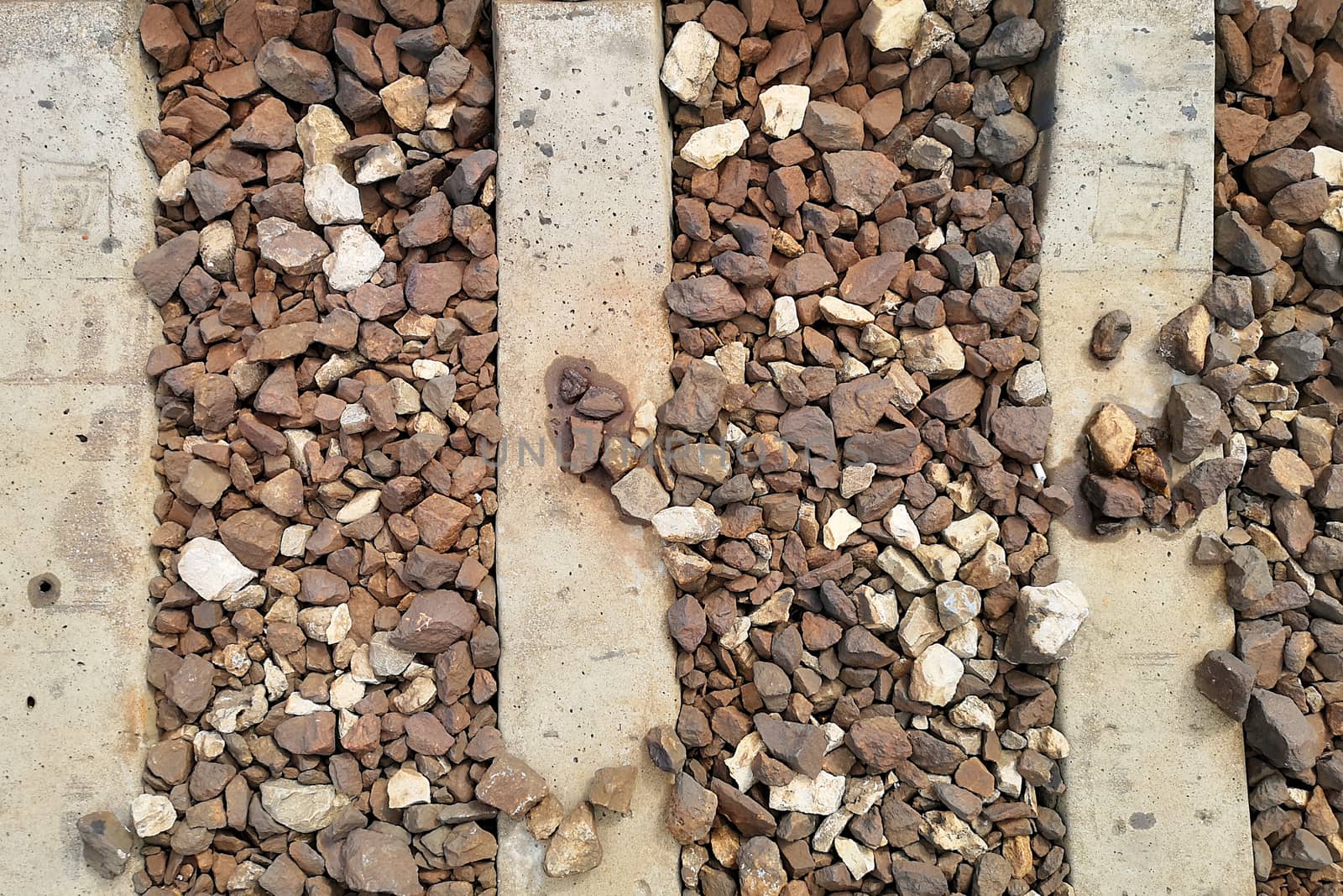 Top view of railway sleeper. concrete structure and embankment of stones. Textures