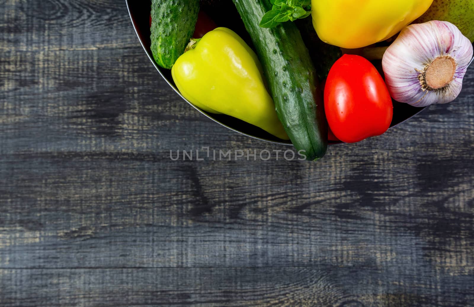 High Angle Still Life View of metal bowl with Fresh Herbs and Assortment of Raw Vegetables on Rustic Wood Table copy space