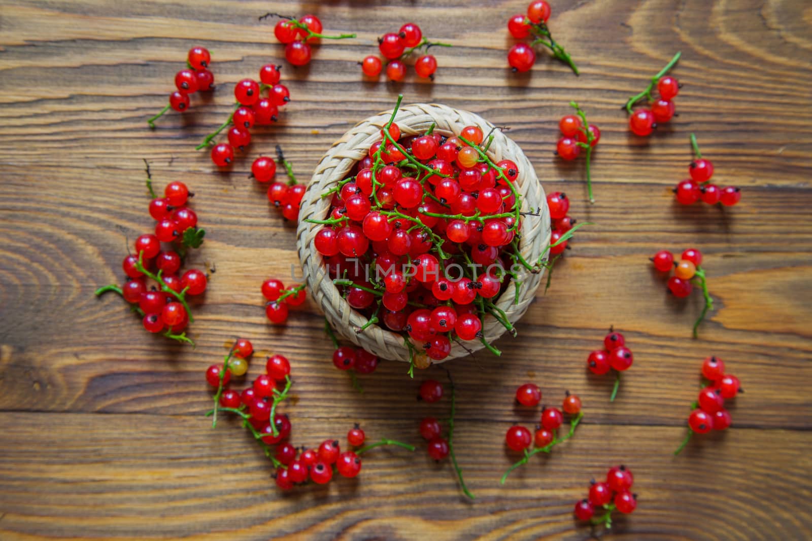 red currant berries in a ceramic bowl on a rustic wooden background. by galinasharapova