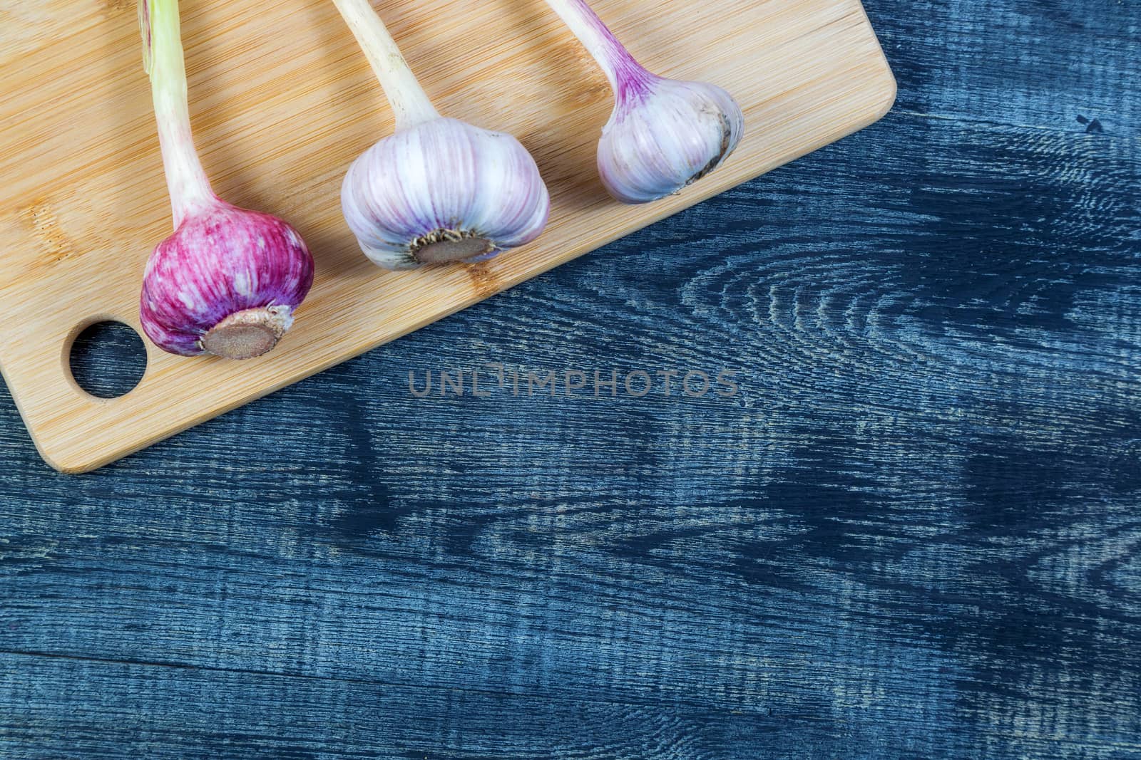 High Angle Still Life View of garlic on Wooden Cutting Board on Rustic Wood Table, copy space