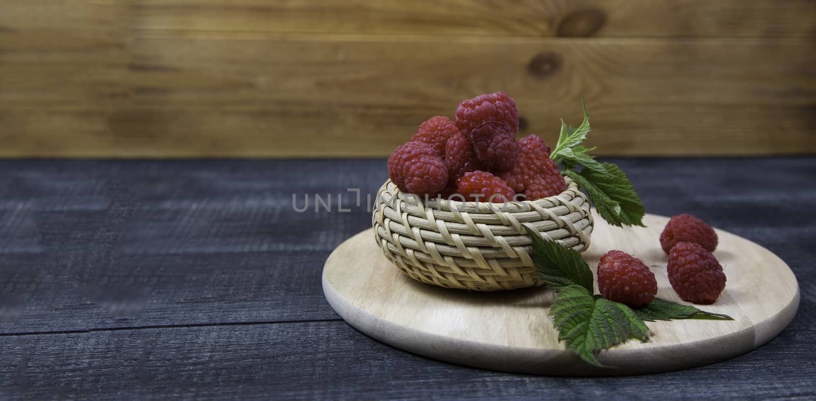 Fresh raspberry in a wicker basket on a wooden background by galinasharapova