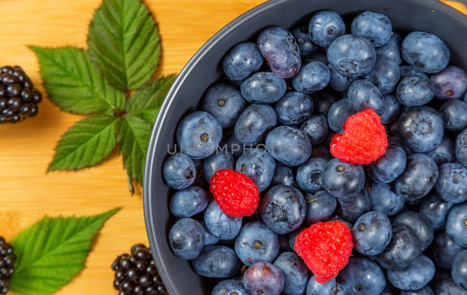 blueberry berry in dark gray ceramic bowl on dark blue wooden background. by galinasharapova