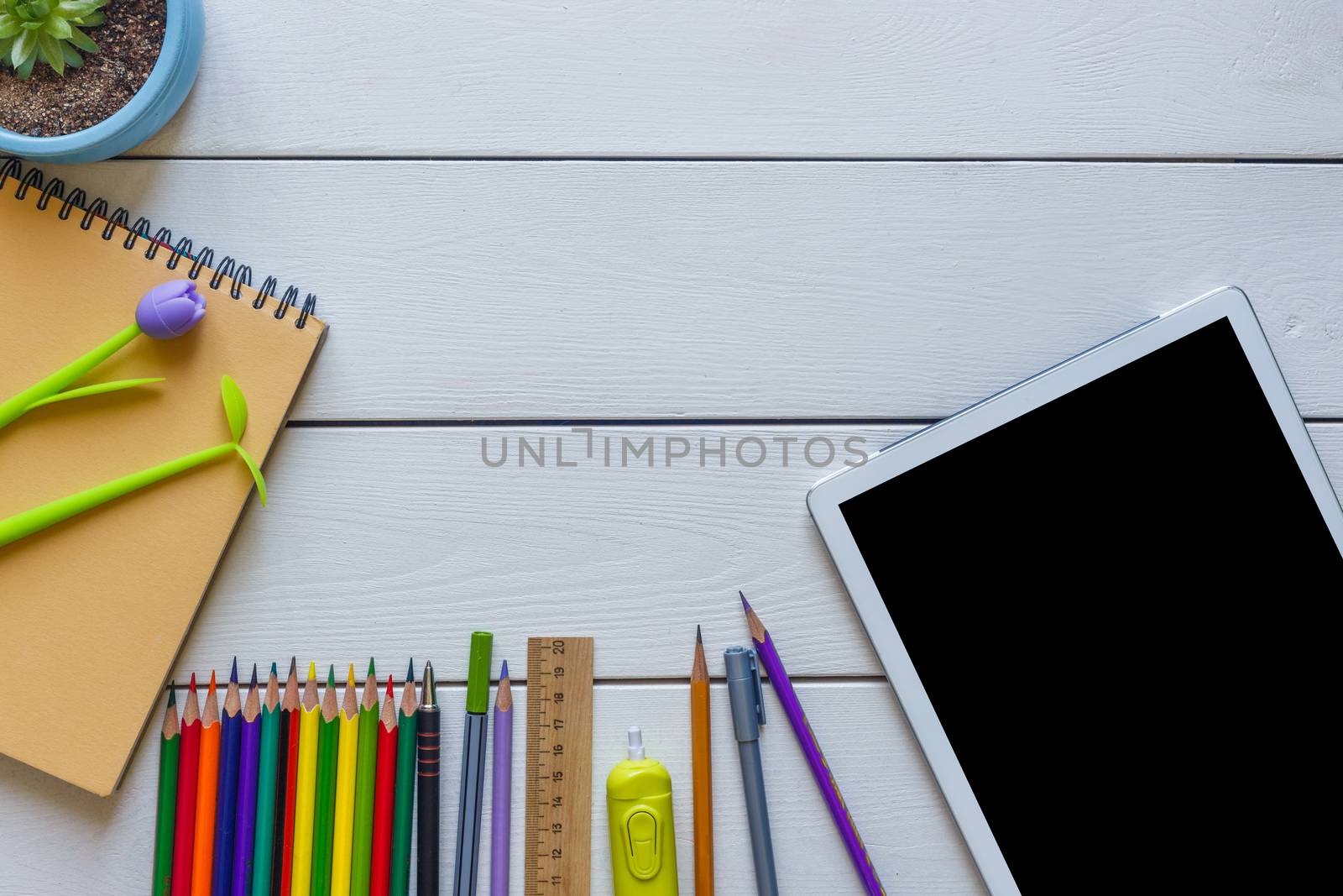 Back to school concept school office supplies on a white wooden background copy space of papers, pencils, alarm clock and tablet.