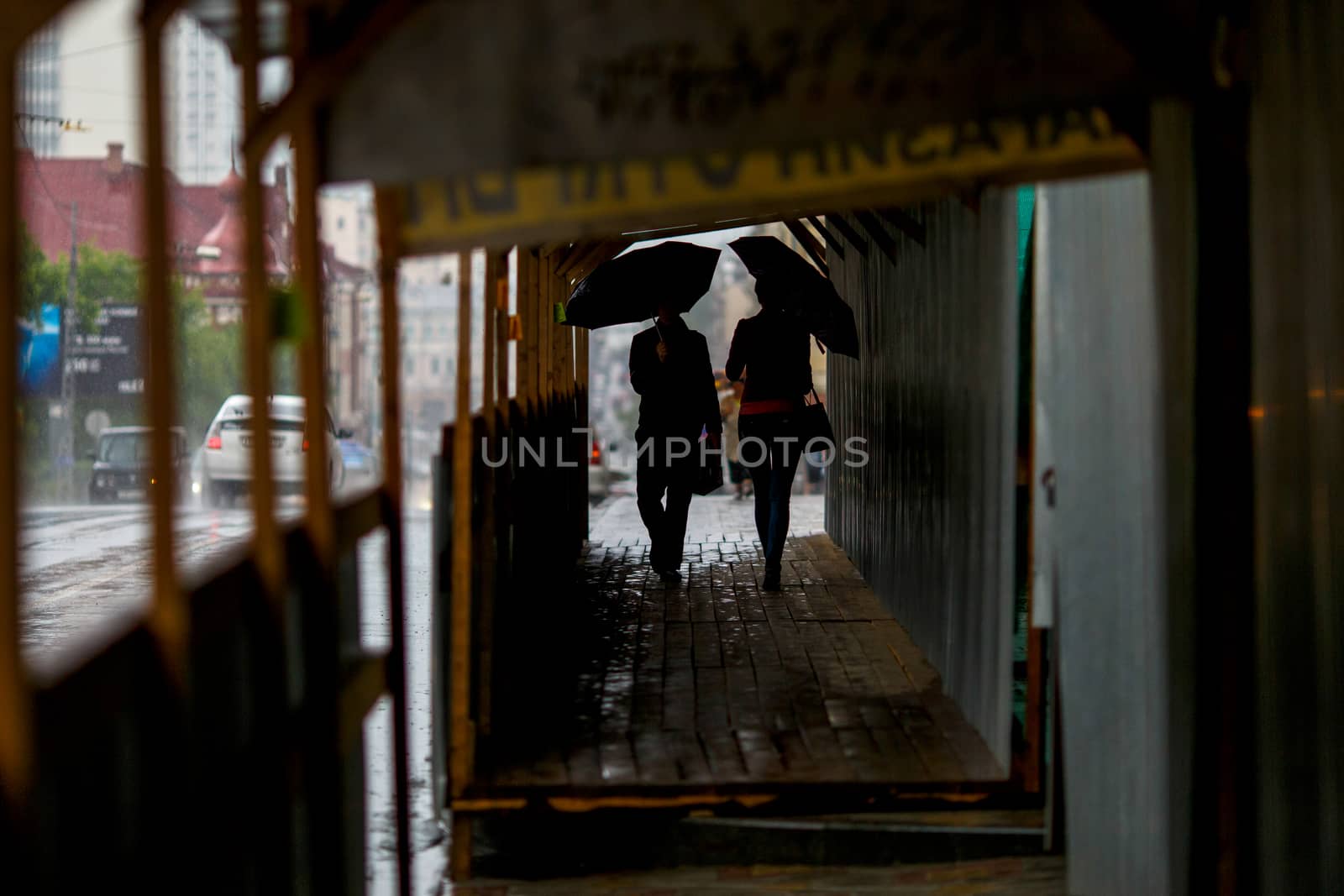 A man walks under an umbrella during the rain, having his face off the camera by PrimDiscovery