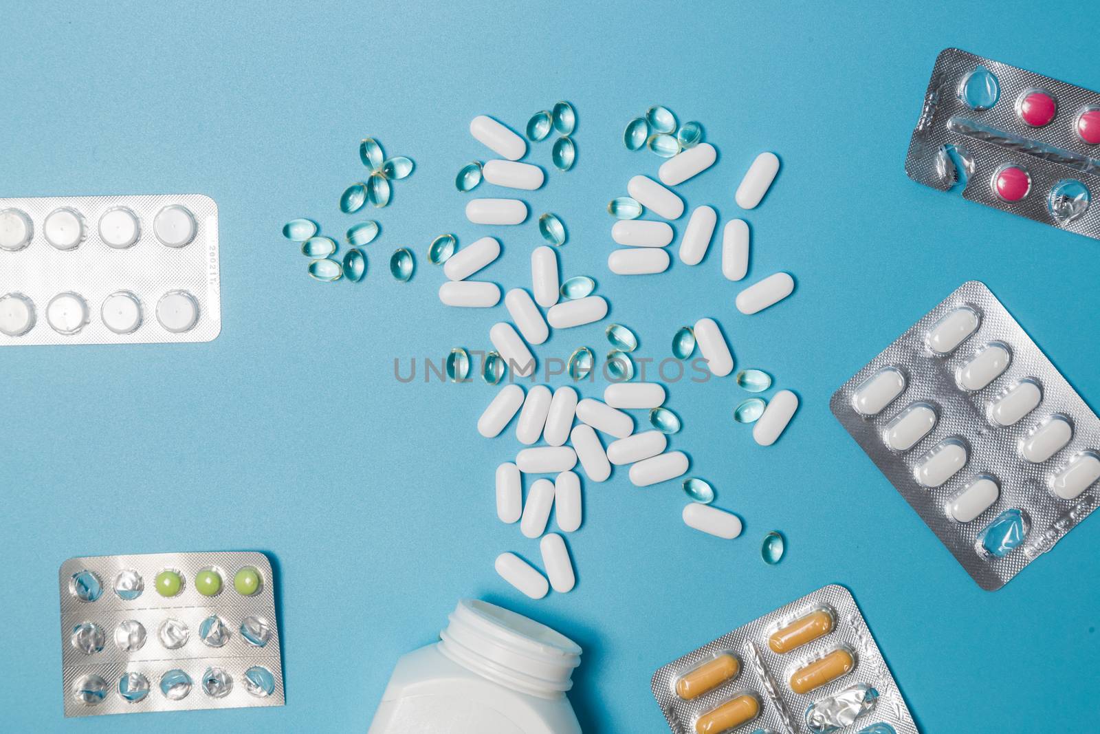 Pharmaceutical tablets, capsules and capsules on a blue background. Copy space for text