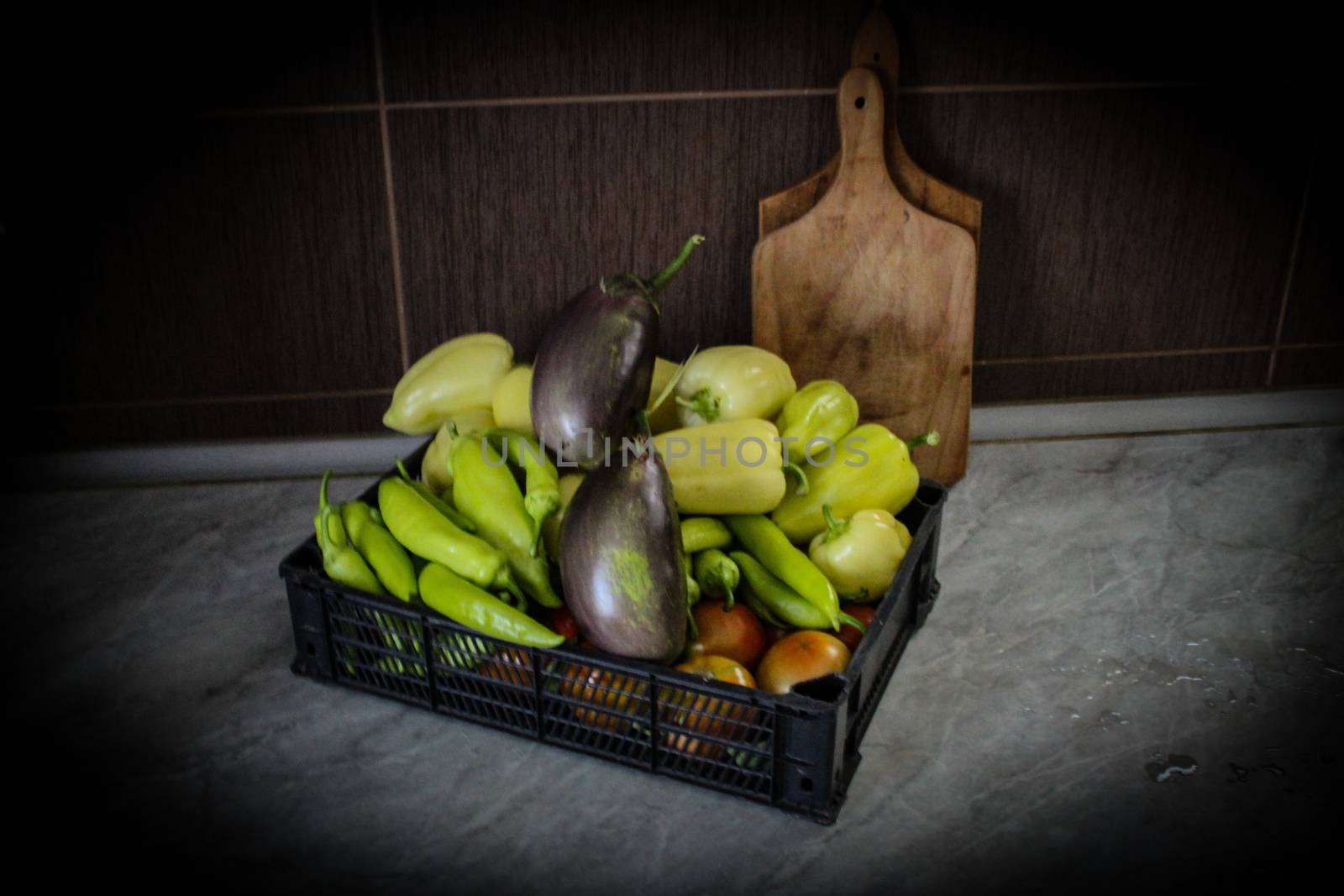 Freshly picked vegetables in a plastic crate, on the kitchen table. Fresh vegetables grown in the garden. Different types of peppers, tomatoes, eggplants, etc. by mahirrov
