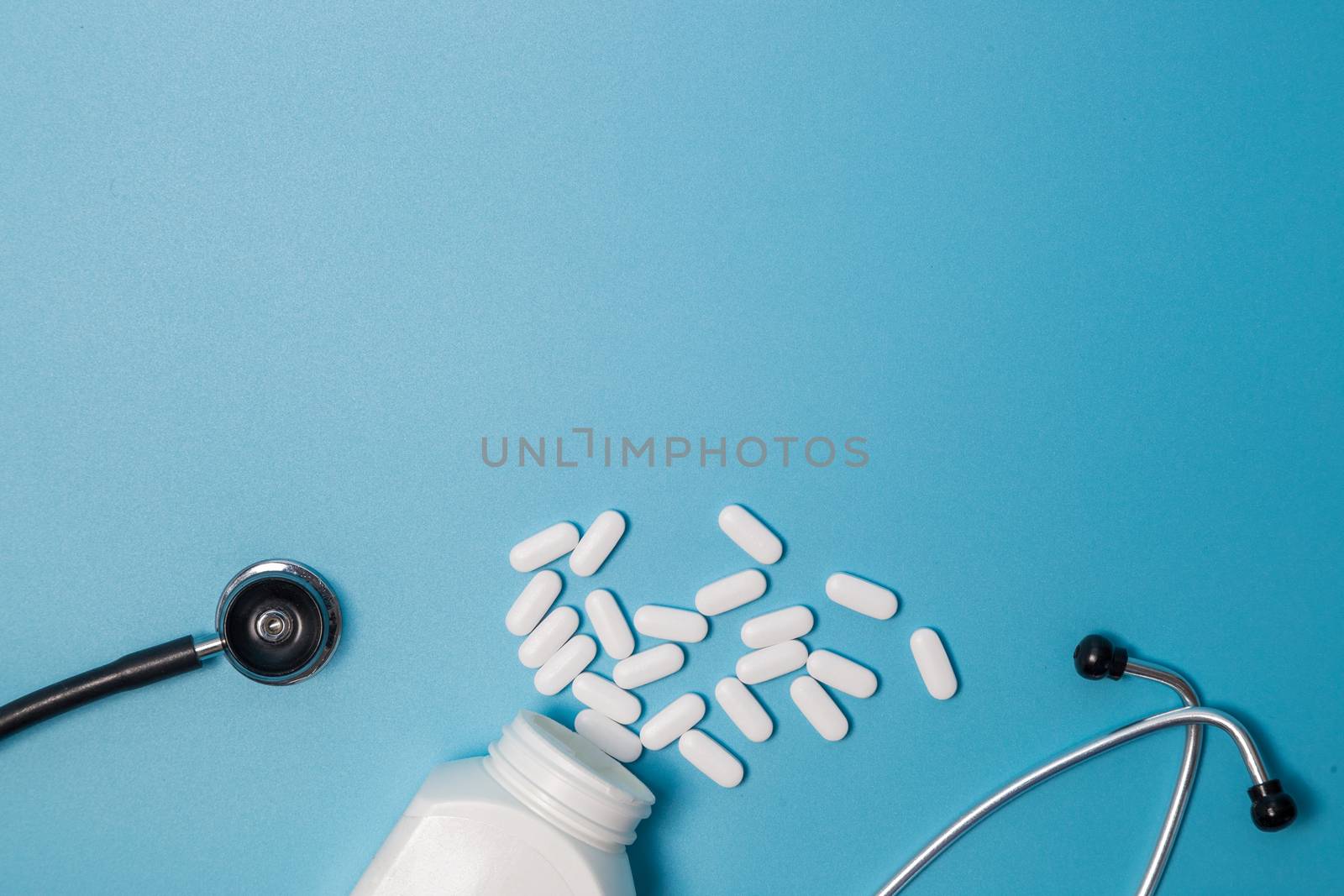 Top view of pills in bottle pack, stethoscope on blue background by galinasharapova