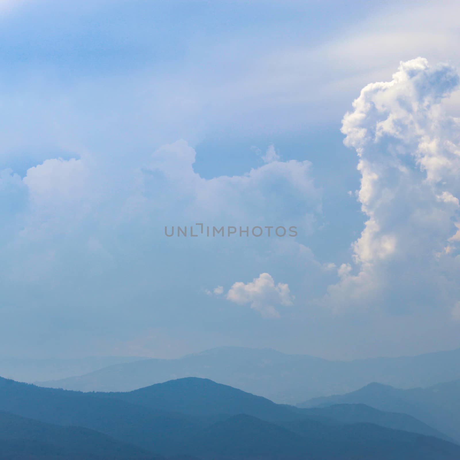 Mountains and hills in the distance. Blue silhouette of a mountain in the distance, with clouds in the blue sky. by mahirrov