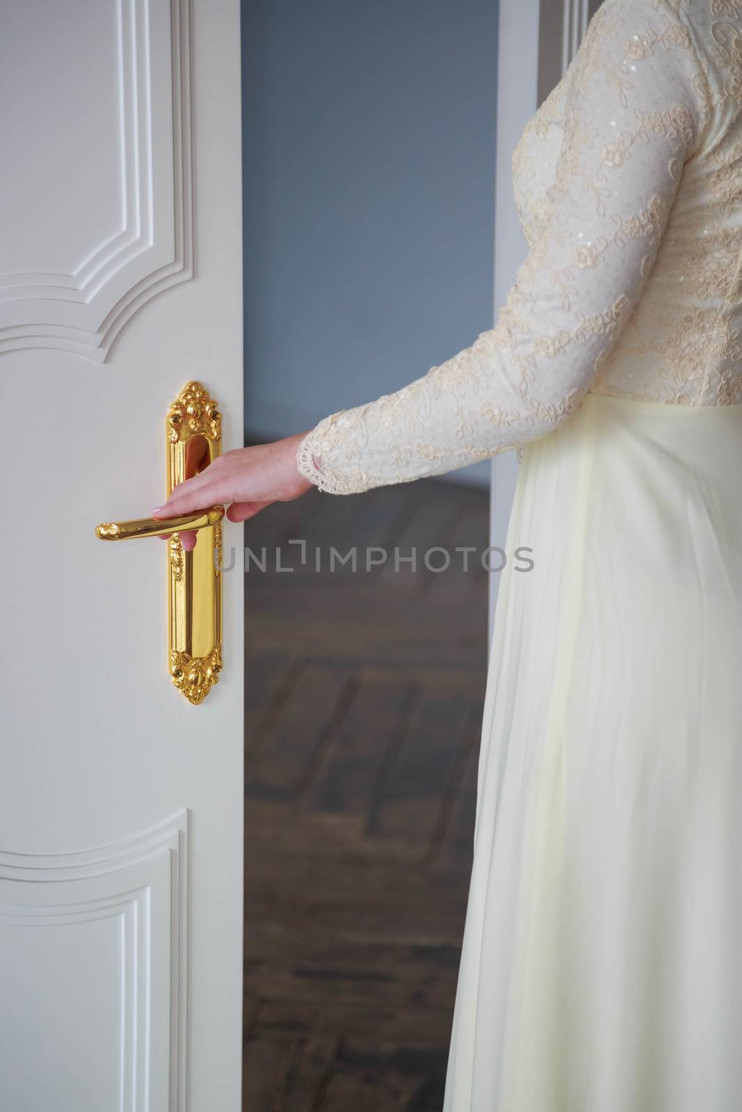 Close-up of the bride's hand opening the door to the wedding ceremony hall.