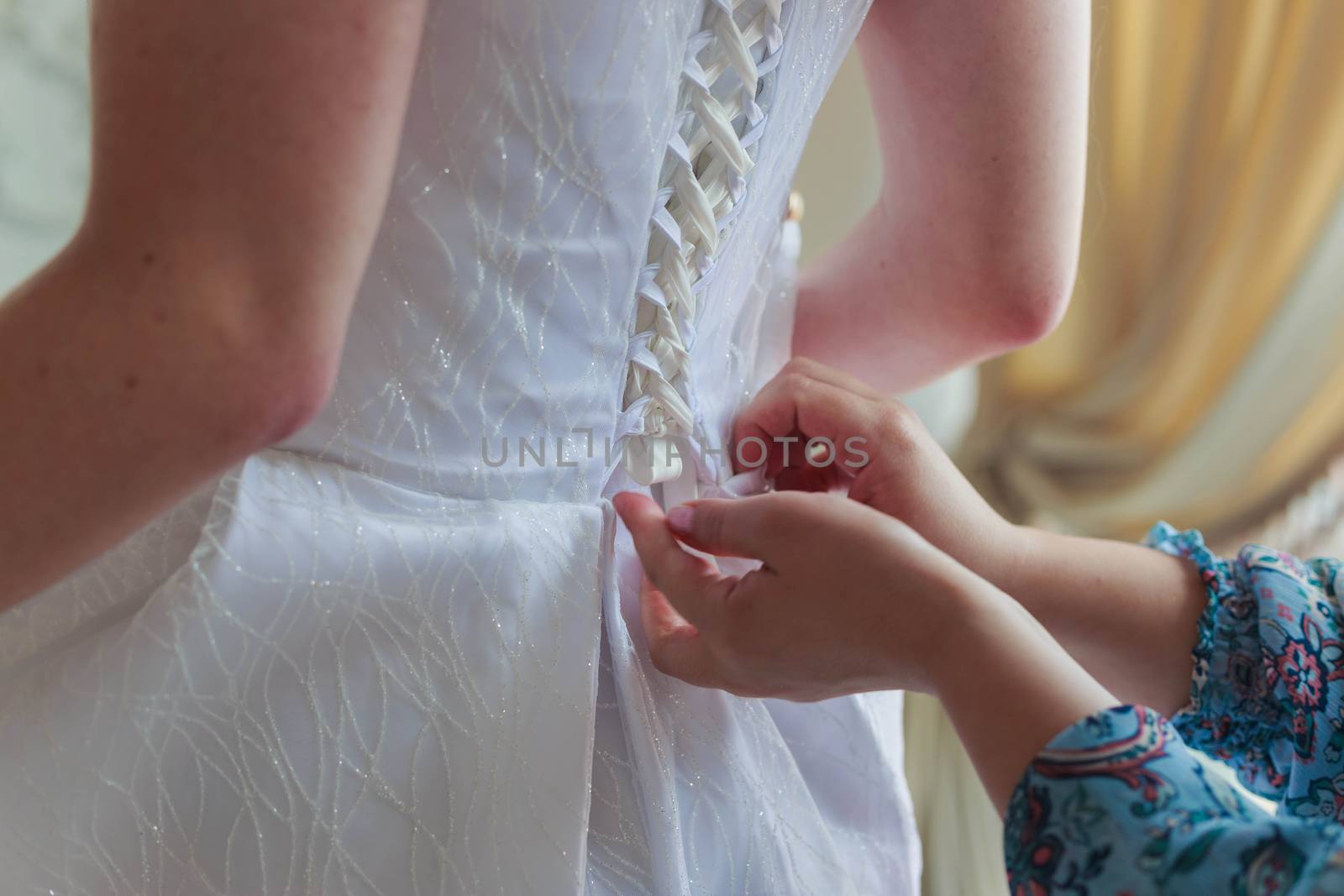 Mother of the bride helps to lace up the dress at the back.