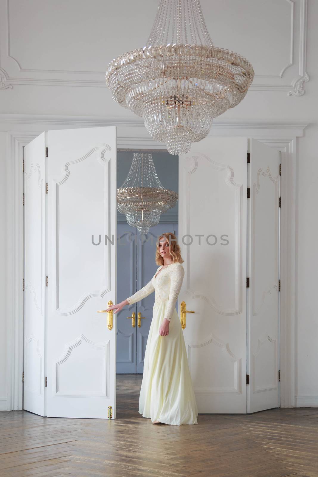 The bride stands at the door in a beautiful white room by galinasharapova