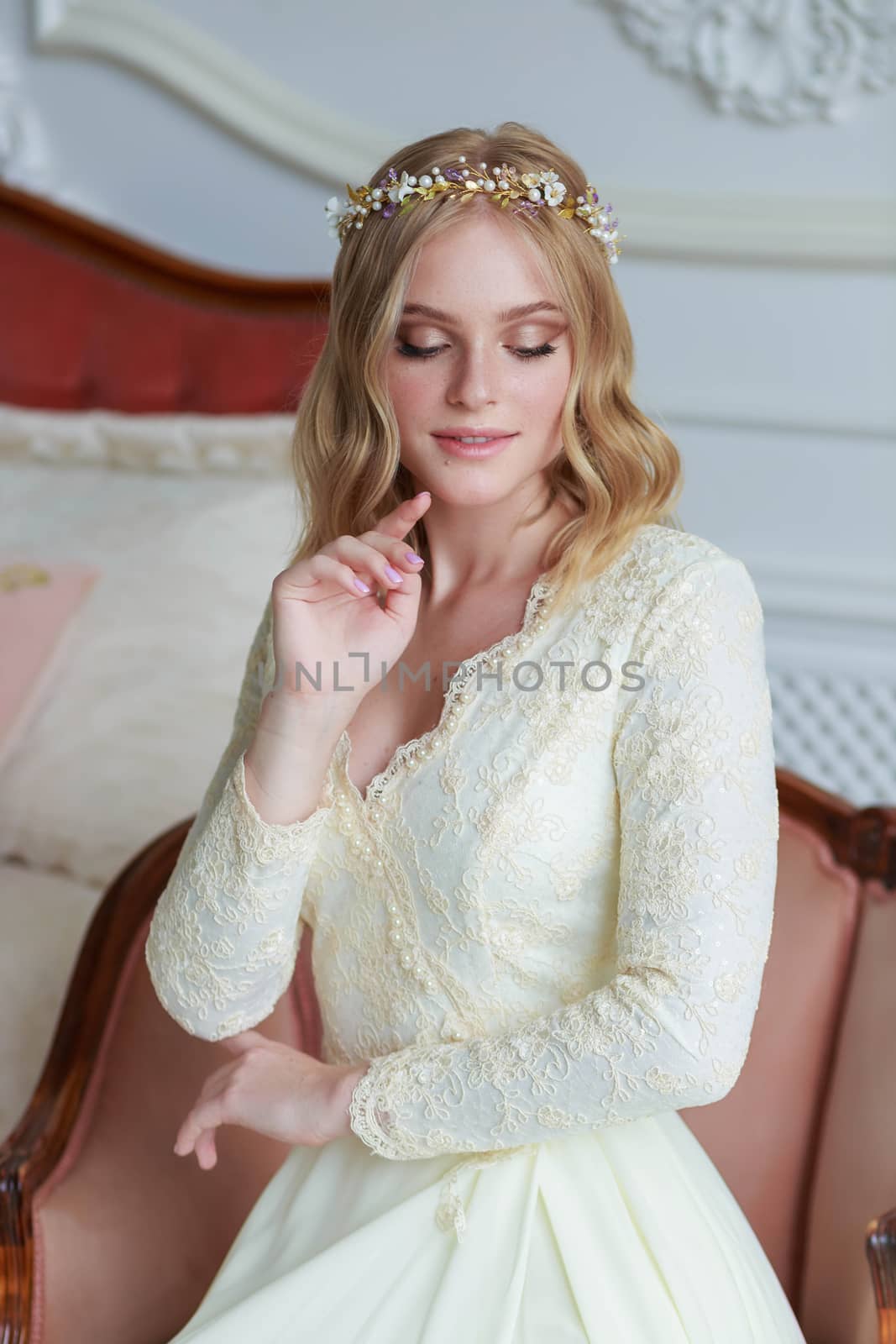 Close-up portrait of a beautiful bride on a wedding day sitting on an armchair.