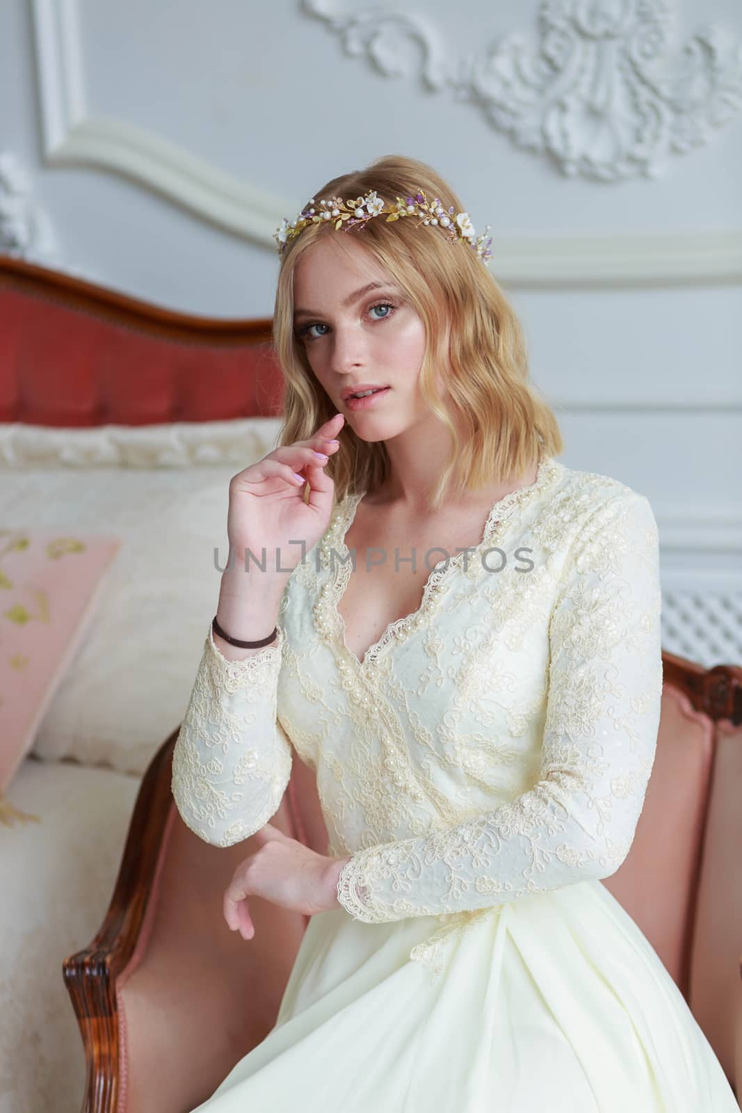 Close-up portrait of a beautiful bride on a wedding day sitting on an armchair.