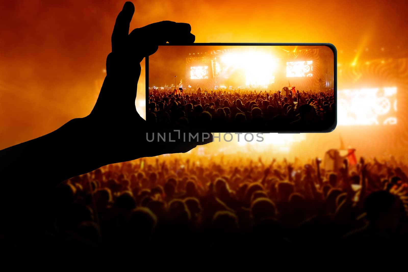 Hand with smartphone records live music concert. Using a mobile phone at the show. by 9parusnikov