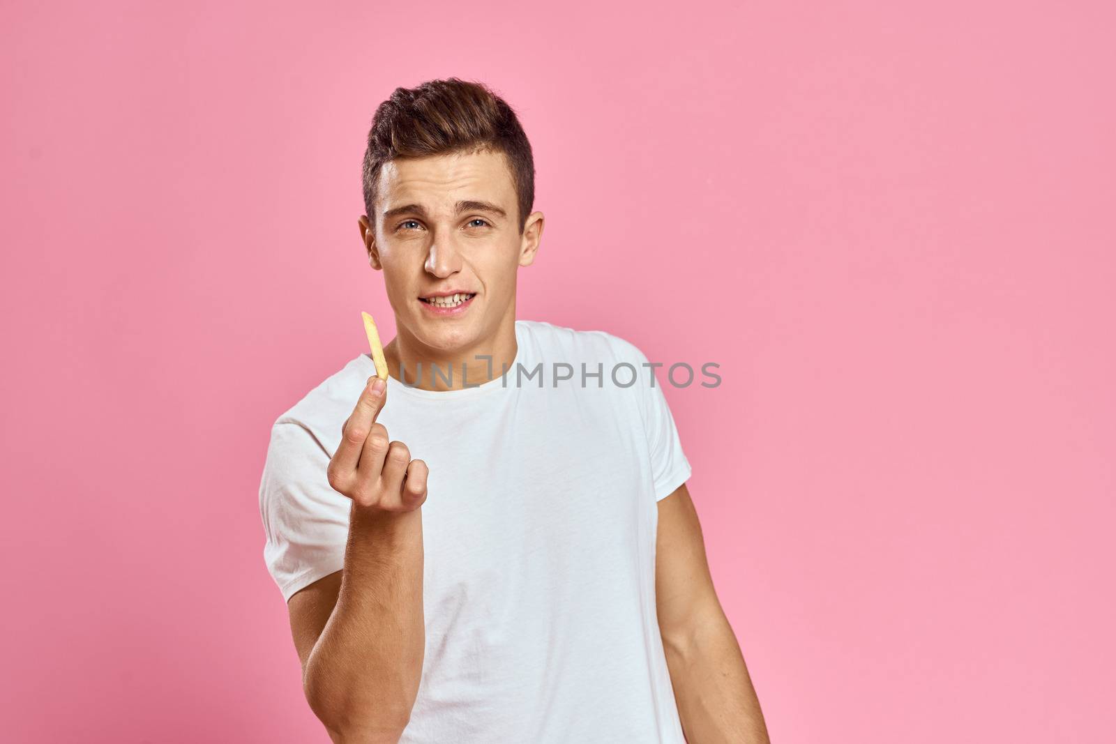 Cute man with fries in hands emotions model fast food pink background cropped view close-up. High quality photo