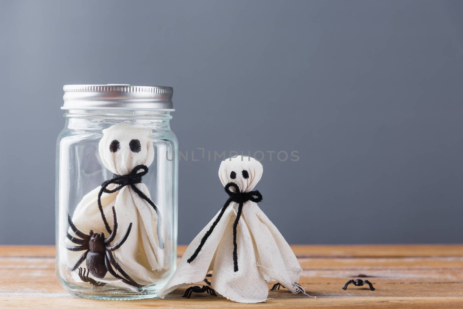 Funny Halloween day decoration party, closeup white ghost and spider in jar on wooden wall gray background and copy space, studio shot isolated, Happy holiday concept