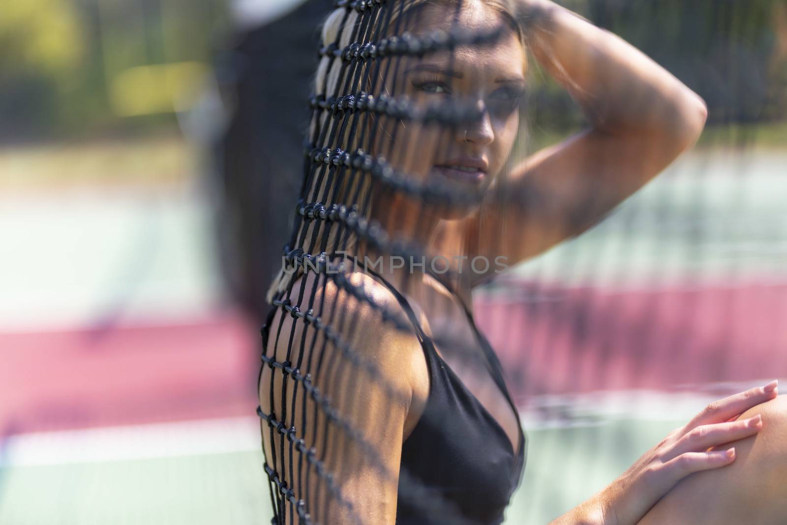 A beautiful blonde model plays tennis on a hot summers day