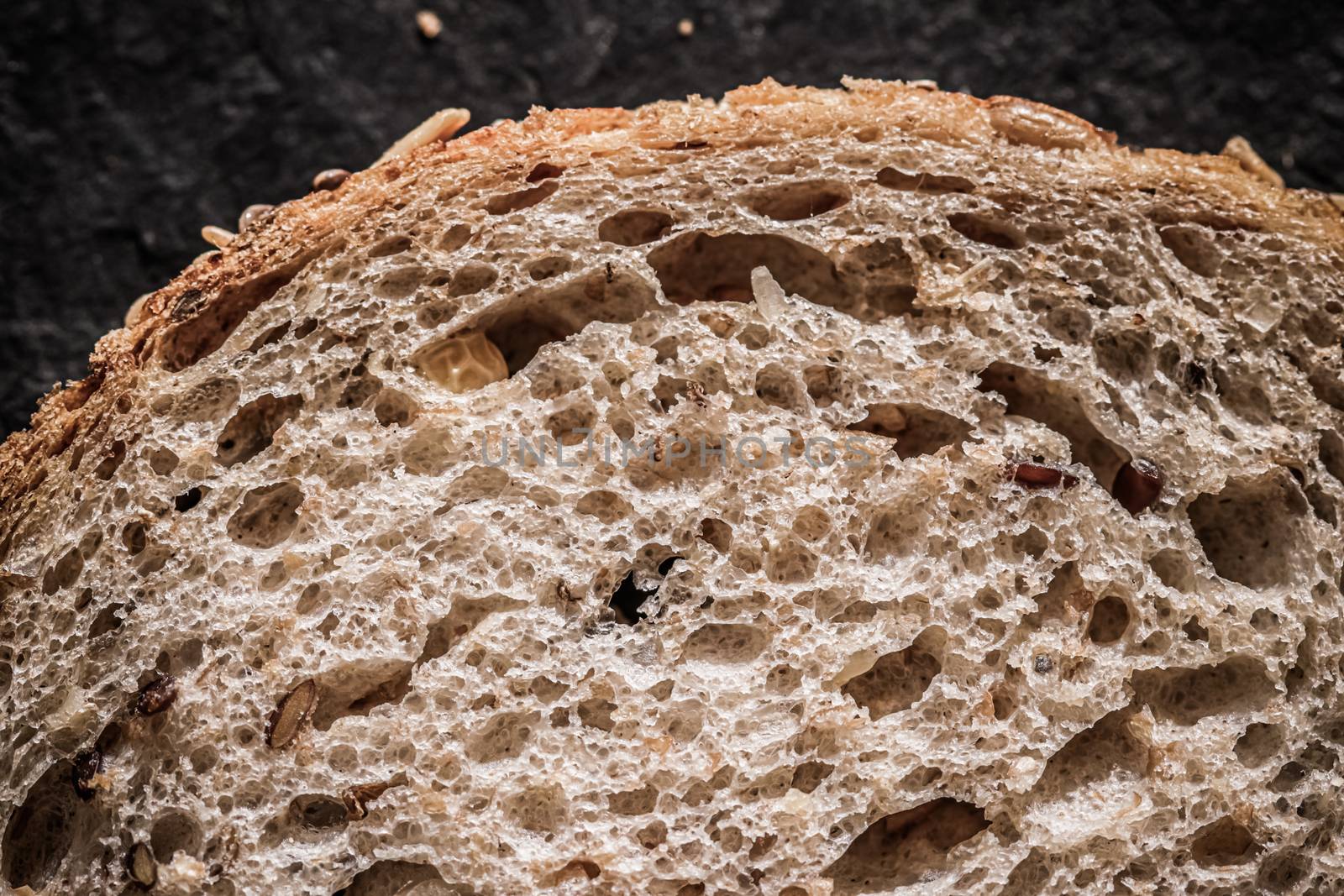 Fresh whole grain seeded bread, organic wheat flour, closeup slice texture as background for food blog or cook book recipe by Anneleven