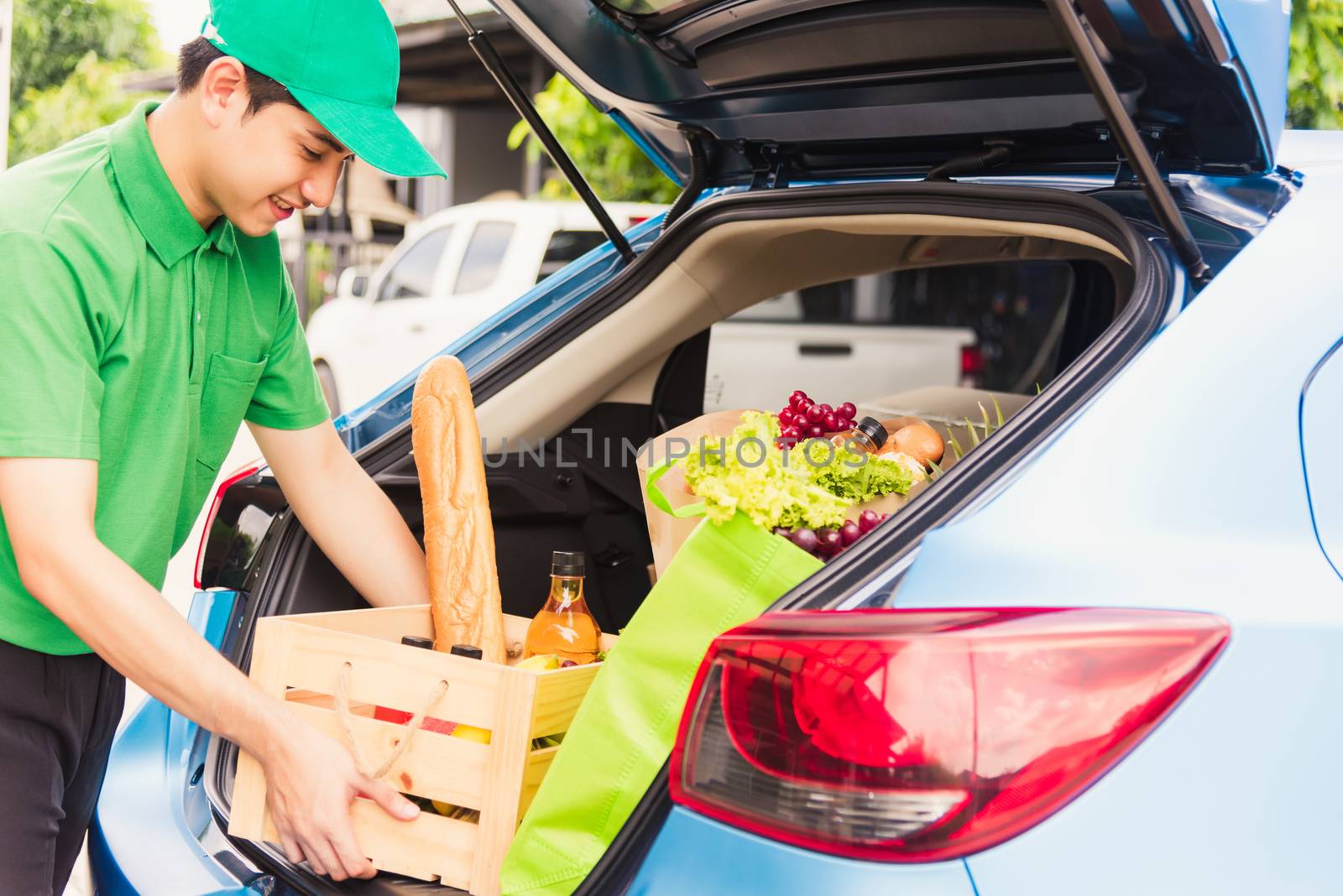 Asian delivery man grocery prepare service giving fresh vegetables food and fruit full in wooden basket on back car to send woman customer at door home after pandemic coronavirus, Back to new normal