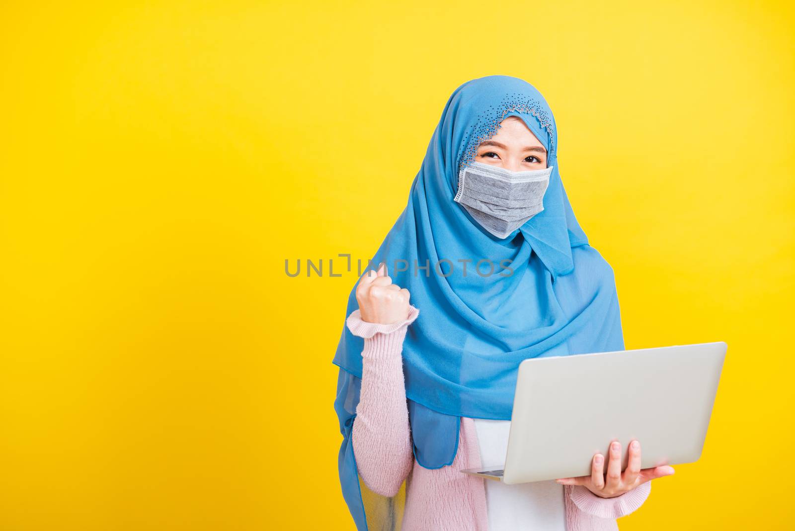 Asian Muslim Arab Portrait of happy beautiful young woman Islam religious wear veil hijab and face mask protect she quarantines disease coronavirus hold laptop computer and raise hand to indicate glad