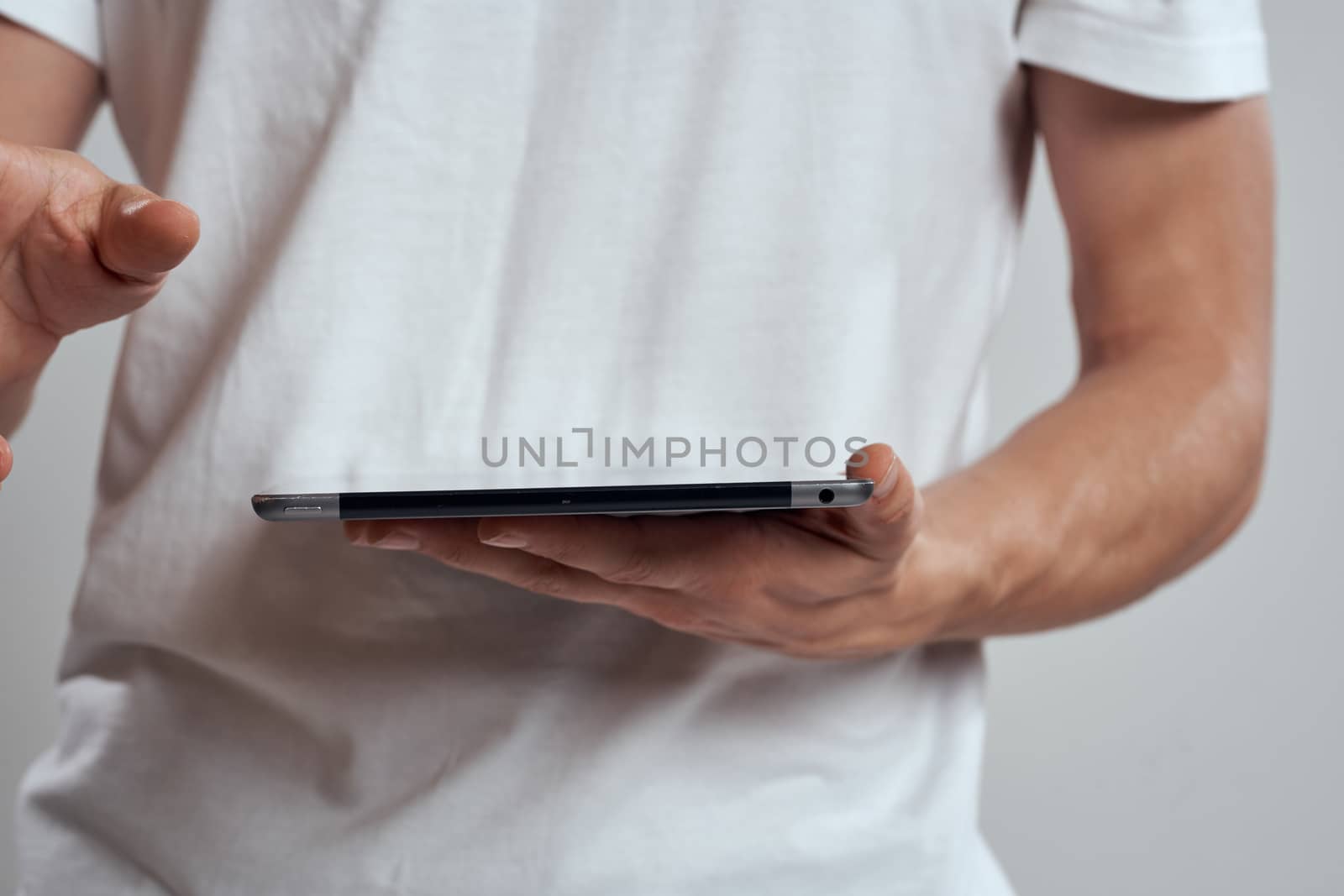 Tablet with a touch screen on a light background male hands white t-shirt cropped view by SHOTPRIME