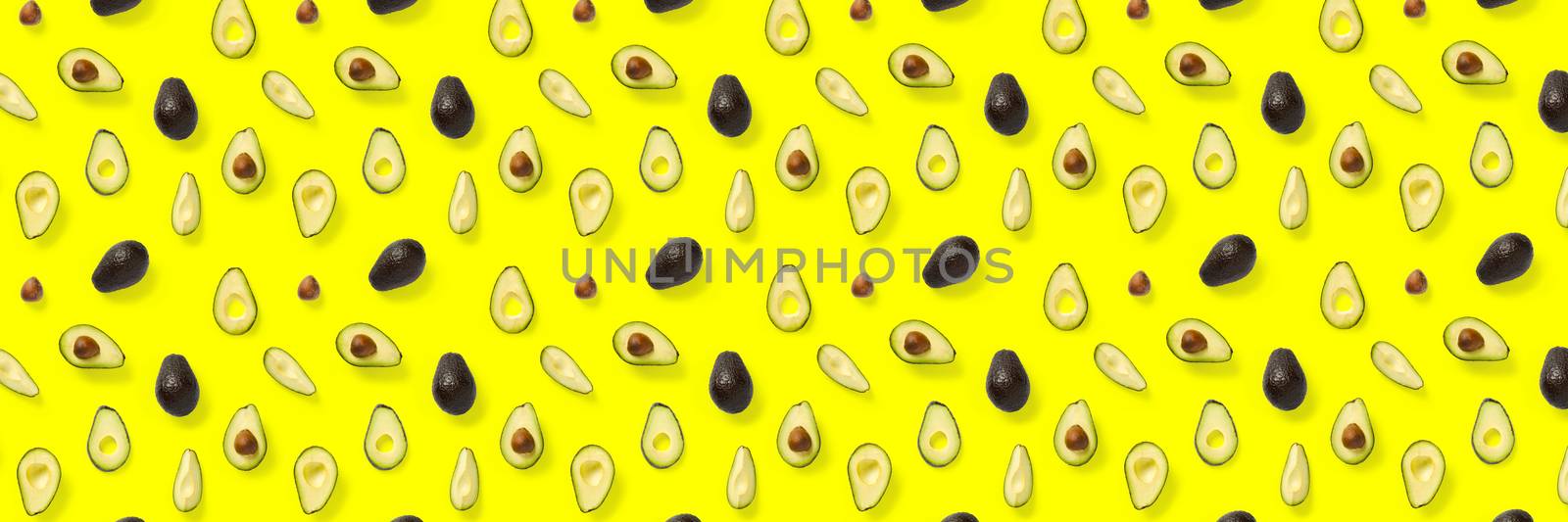 Avocado banner. Background made from isolated Avocado pieces on yellow background. Flat lay of fresh ripe avocados and avacado pieces. by PhotoTime