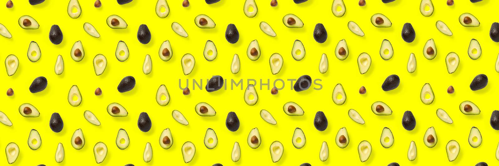 Avocado banner. Background made from isolated Avocado pieces on yellow background. Flat lay of fresh ripe avocados and avacado pieces