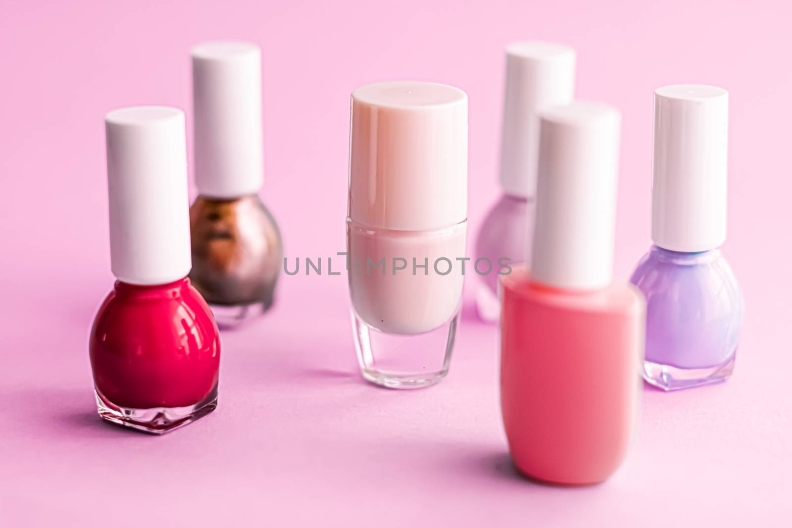 Nail polish bottles on pink background, beauty brand by Anneleven