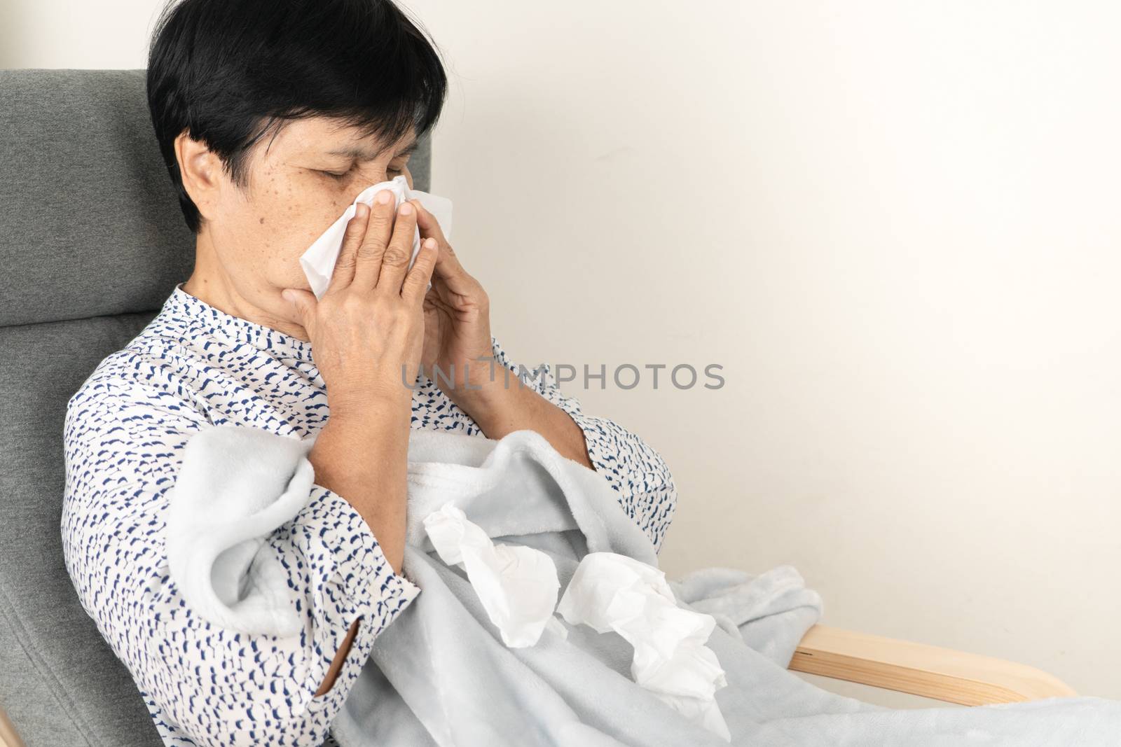 sick senior woman with dirty tissue. ill person wearing blanket woolen lay down on sofa