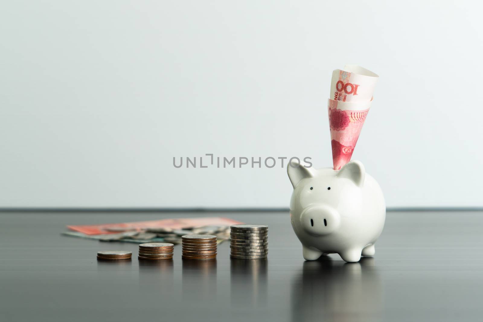 Money saving and donation concept, money on cute white piggy bank on table