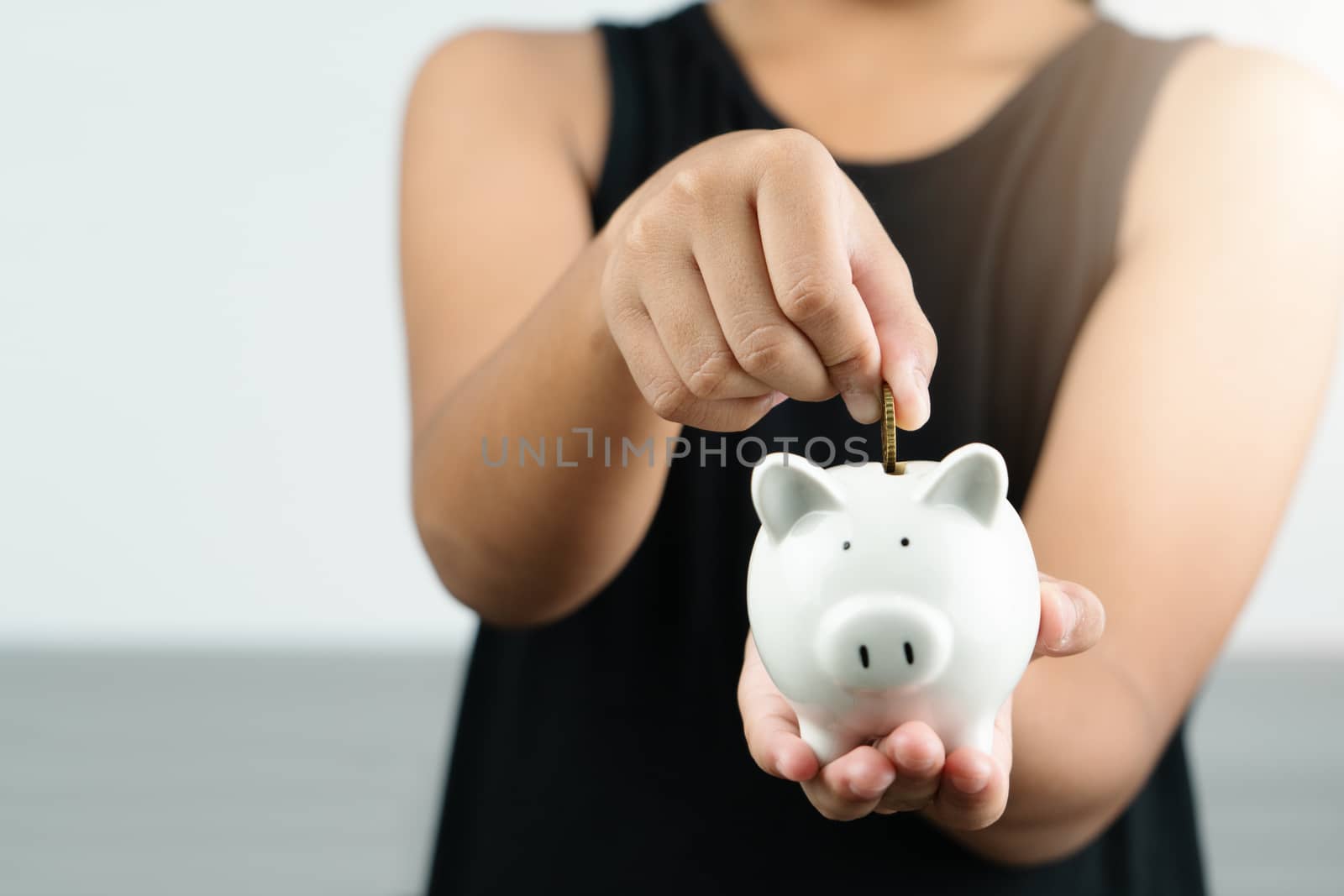 Money saving and donation concept, child put money on cute white piggy bank