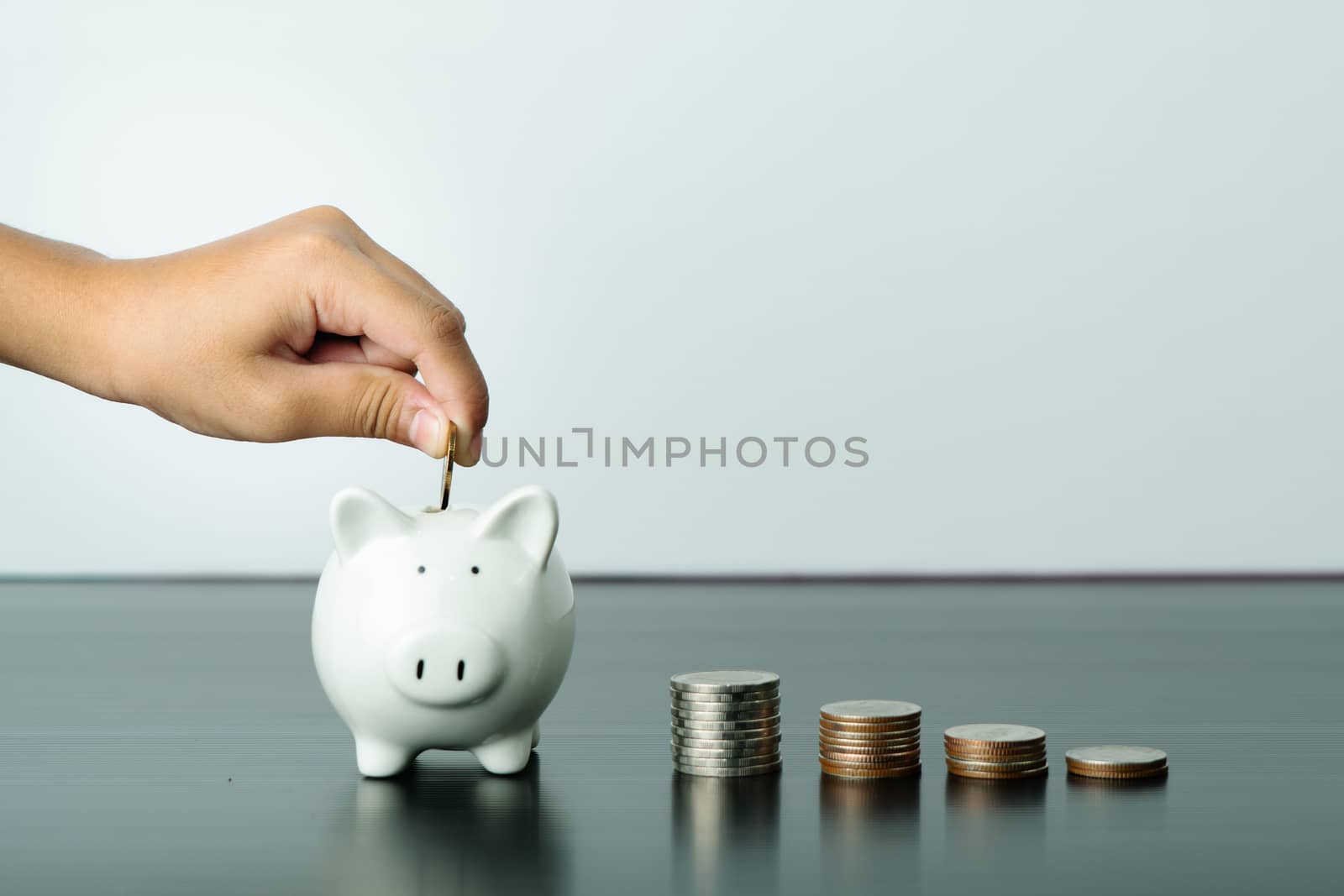 Money saving and donation concept, child put money on cute white piggy bank